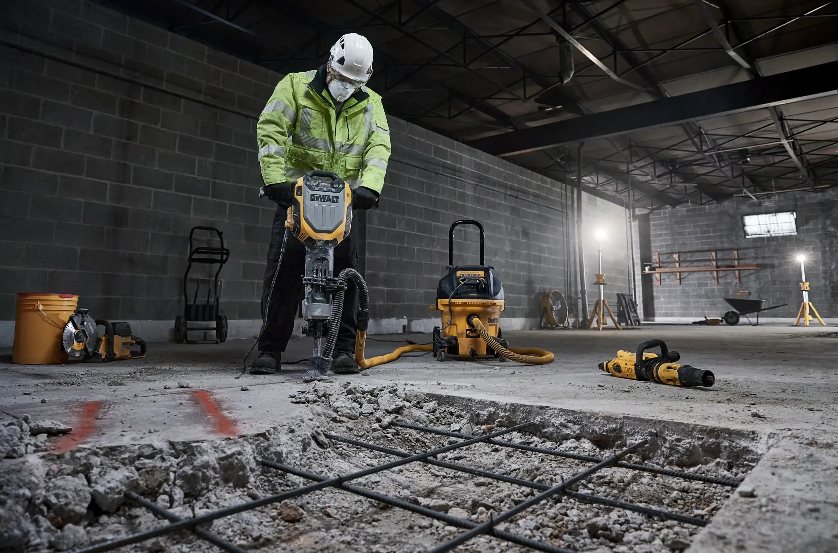 Trabajador usa DEWALT D25966, D25966-B2 en hormigón de almacén. Herramientas de construcción visibles.