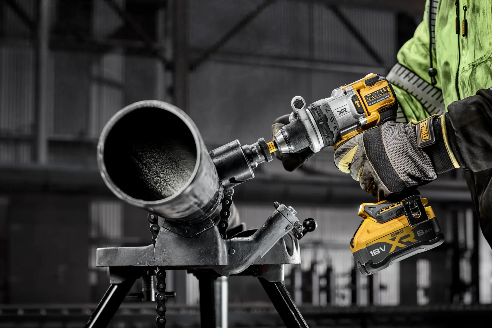 Arbeiter bohrt mit DEWALT XR 18V Akku-Werkzeug in ein Metallrohr in industrieller Umgebung.