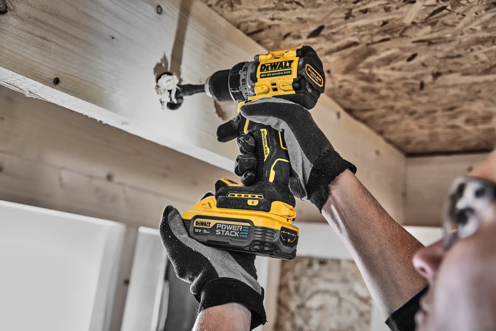 Persona usa taladro inalámbrico DEWALT con batería POWERSTACK para perforar una viga de madera.