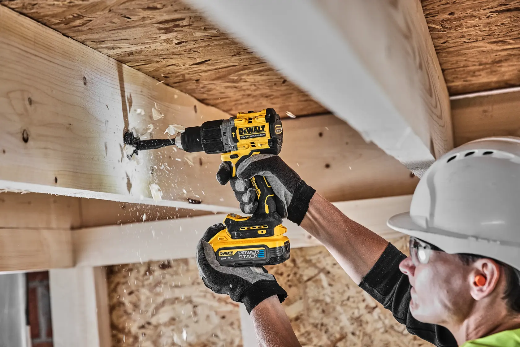 Persona utiliza taladro inalámbrico DEWALT para perforar una viga de madera, salen astillas.