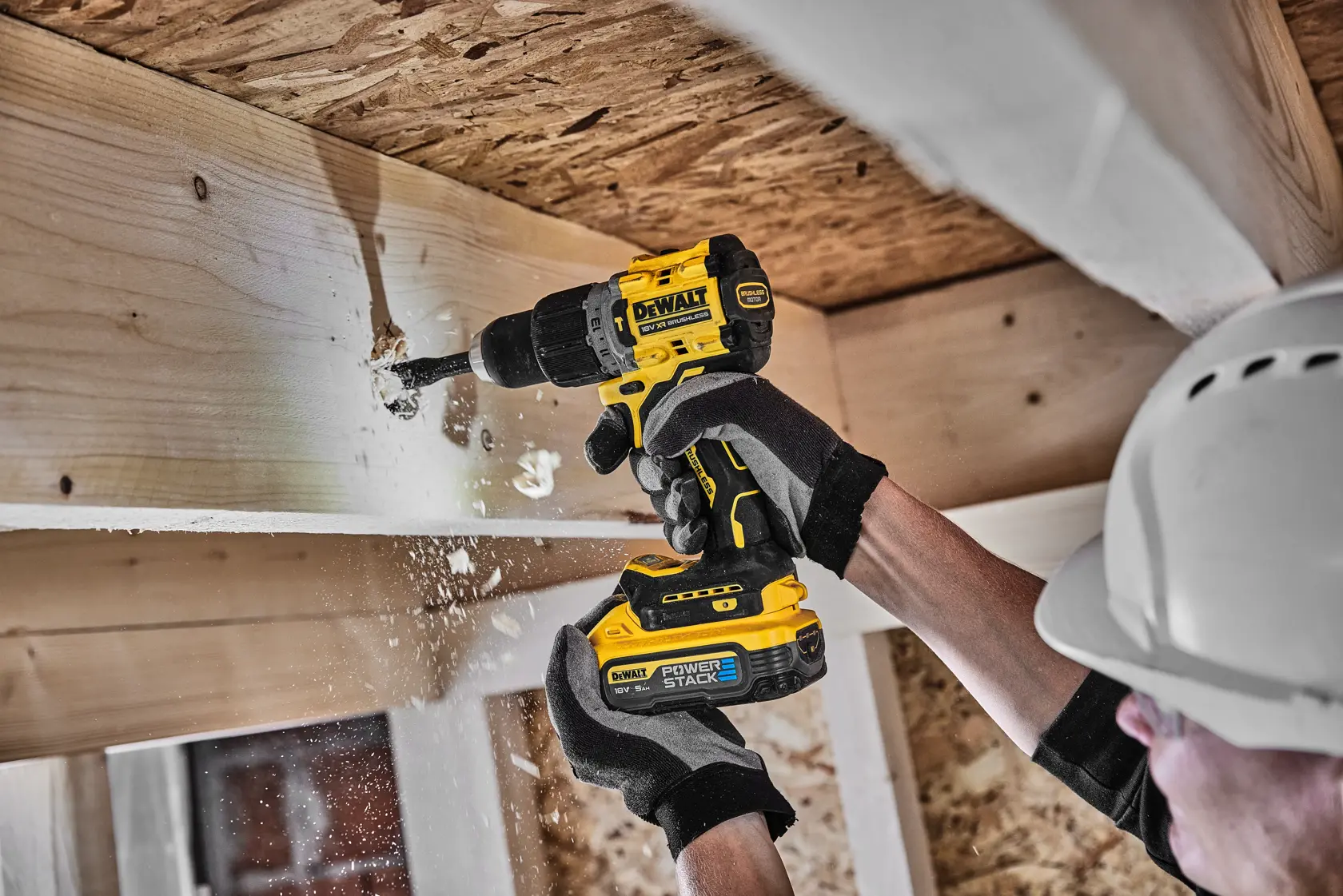 Persona usa taladro DEWALT para perforar viga de madera, con guantes y casco.