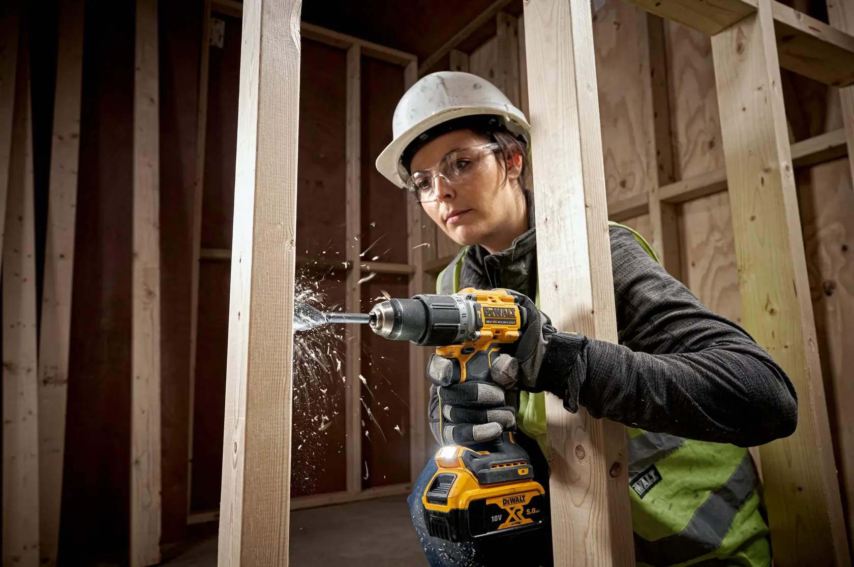 Persona usa un trapano a batteria DEWALT per forare travi di legno in un cantiere.