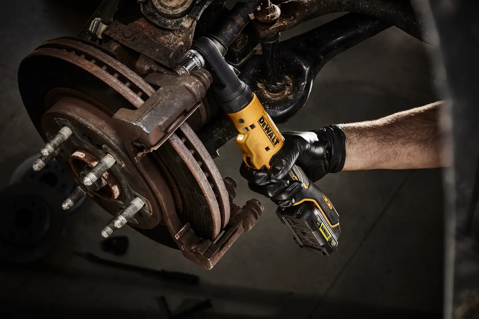 Persona usa herramienta de carraca DEWALT inalámbrica en freno de vehículo.