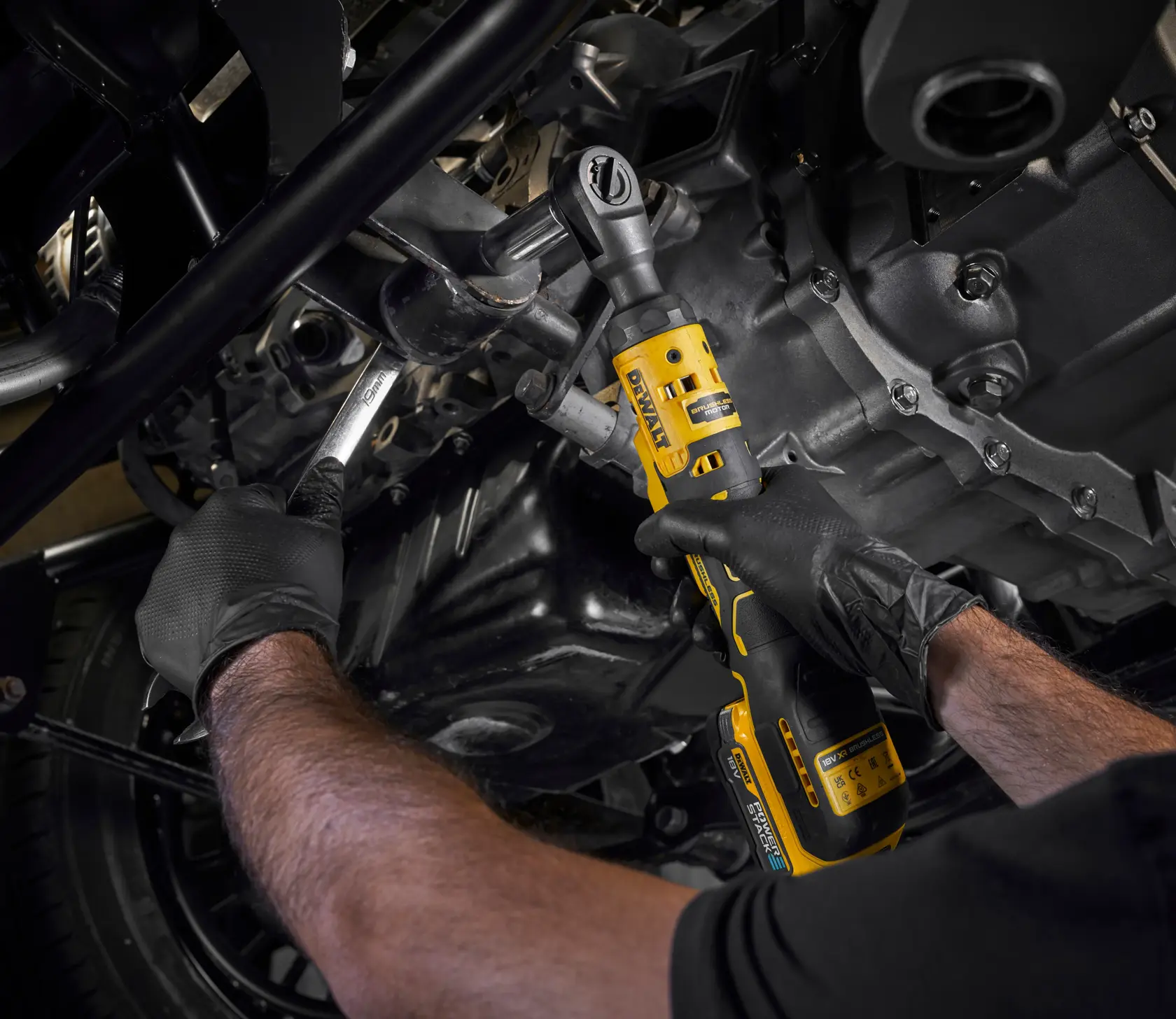 Person nutzt einen DEWALT DCF512N Akku-Ratschenschlüssel am Motor und trägt Handschuhe.