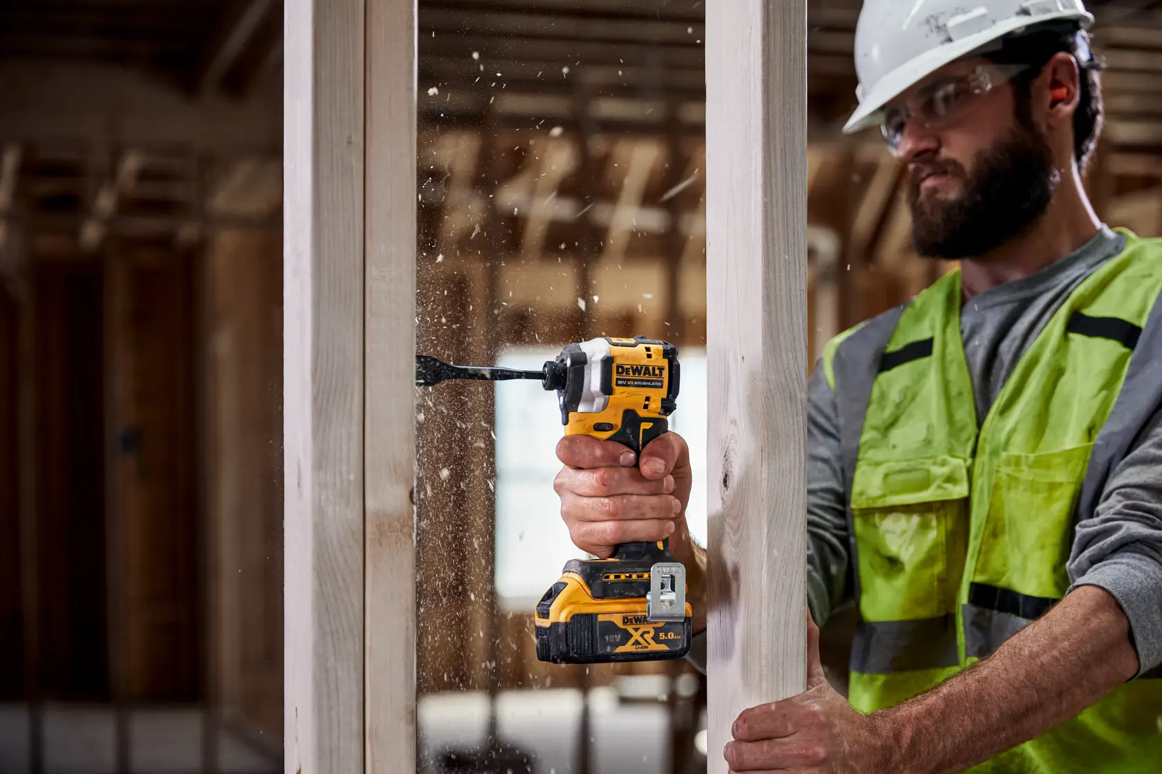 Persona usa taladro inalámbrico DEWALT para perforar viga de madera en obra.