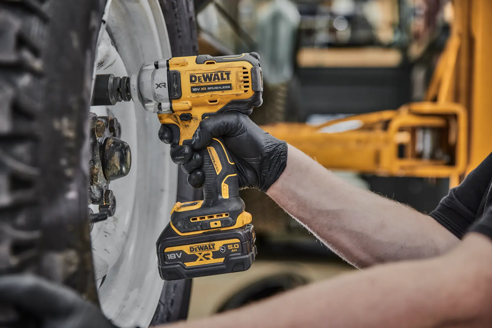 Person uses DEWALT cordless impact wrench to tighten bolts on a vehicle wheel.