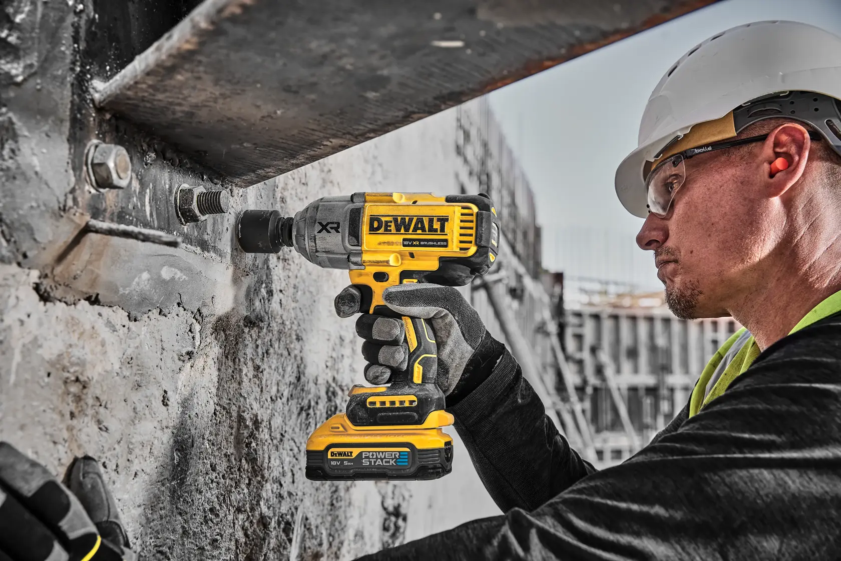 Trabajador usa una llave de impacto inalámbrica DEWALT sobre estructura de concreto.