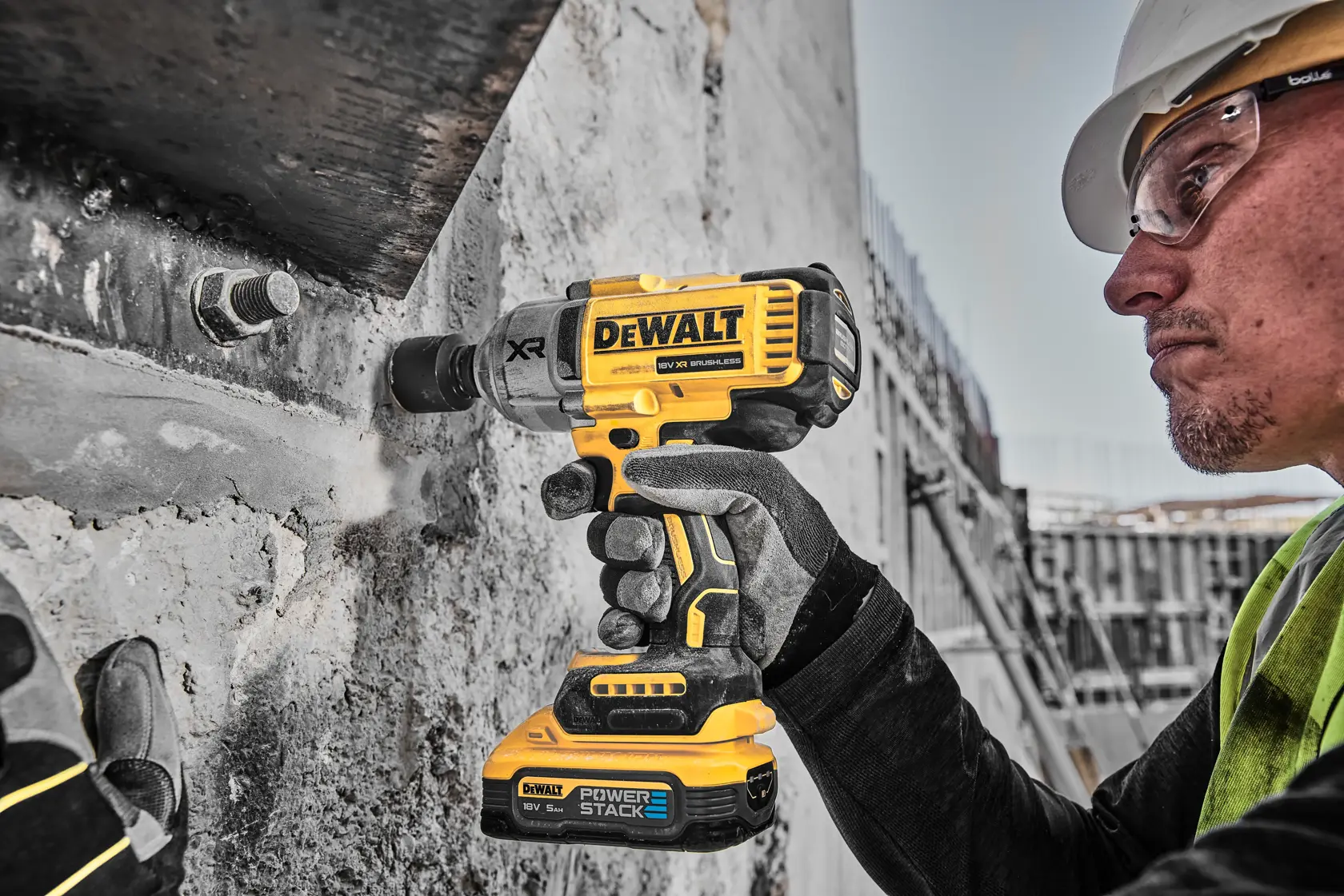 Trabajador usa llave de impacto DEWALT DCF900H2T amarilla en concreto en obra.