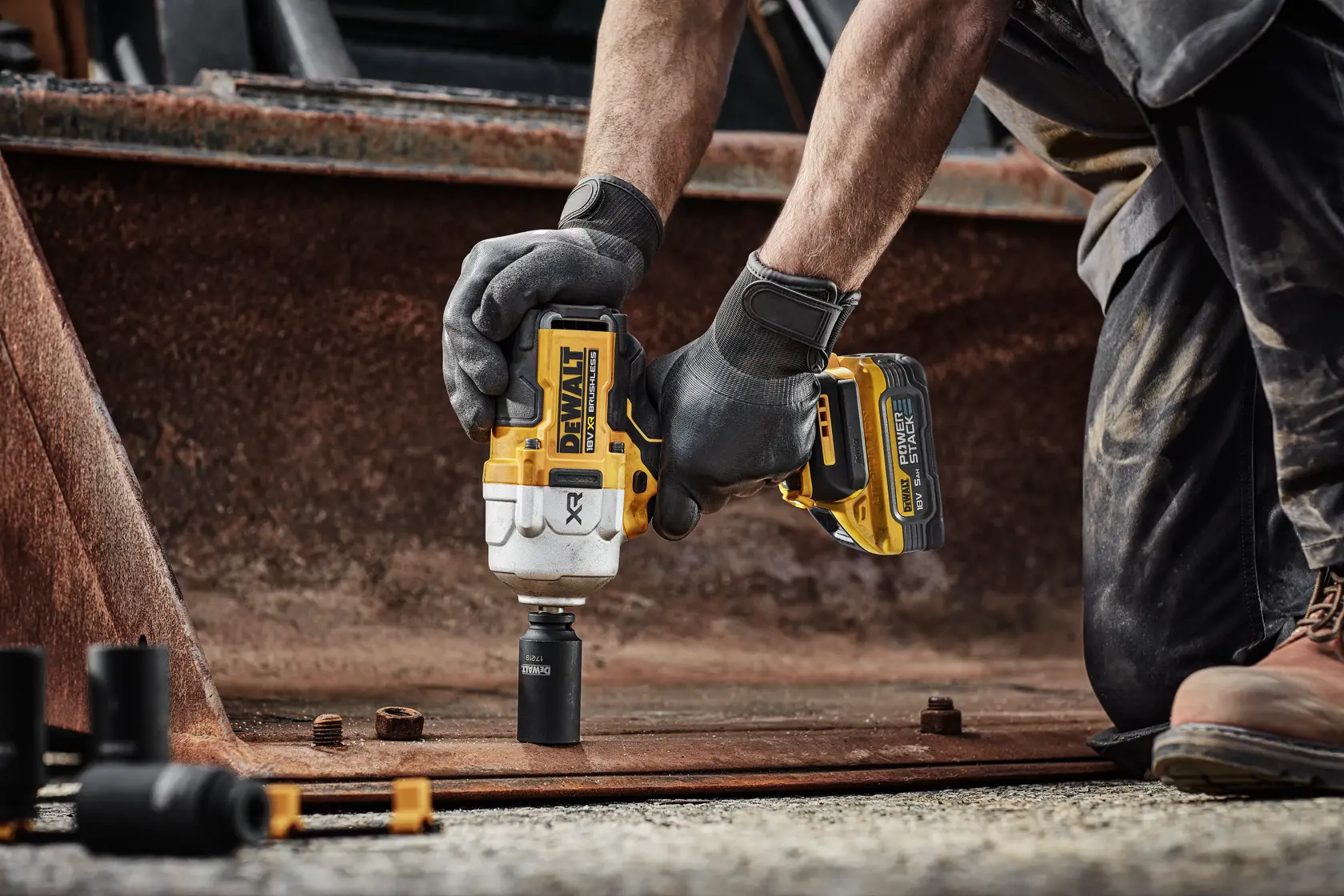 Llave de impacto DEWALT DCF961H2T usada en metal oxidado por una persona con guantes.