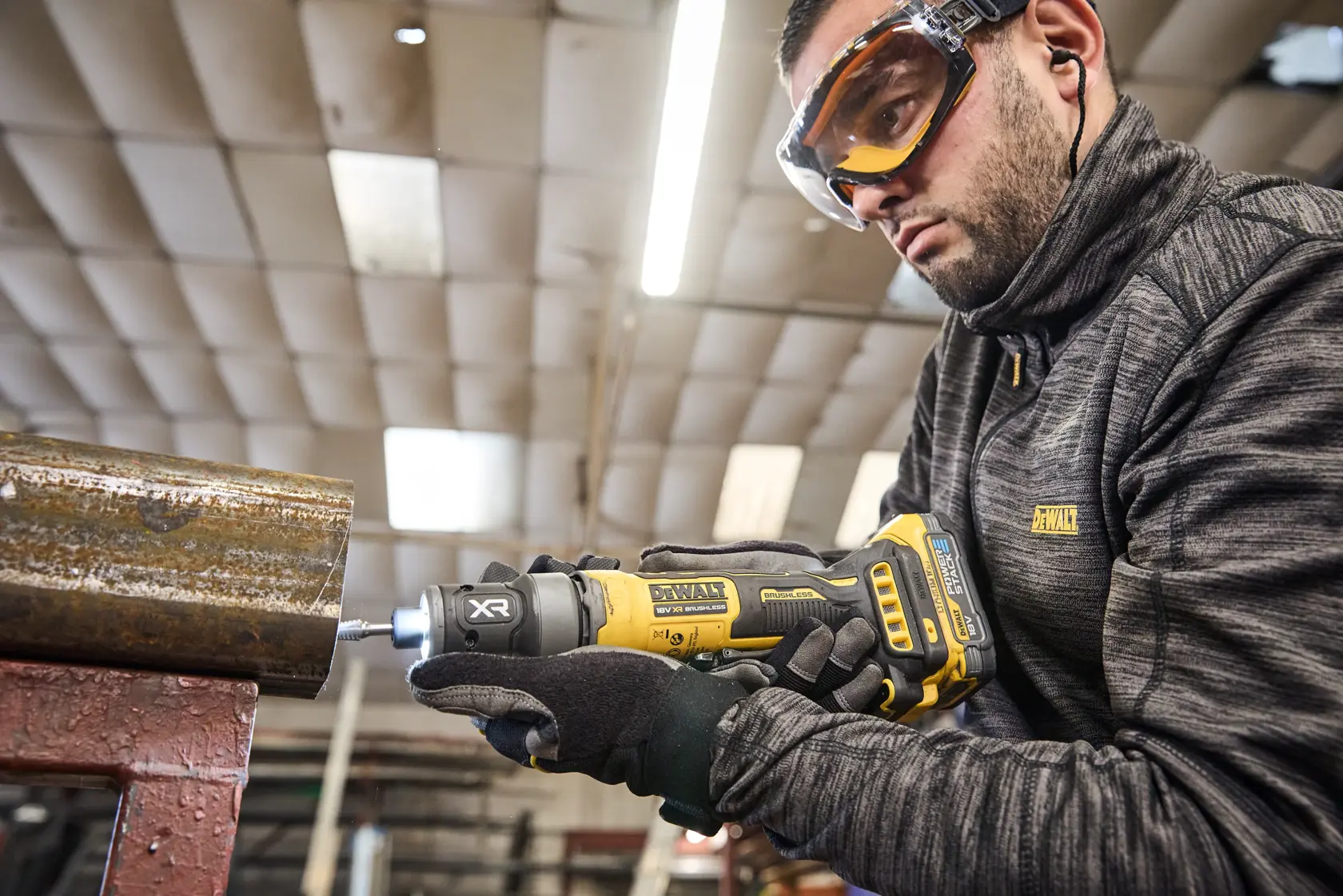 DEWALT DCG420N-XJ, DCG420N usado en tubo metálico. Usuario con ropa DEWALT. Categoría fotografía.