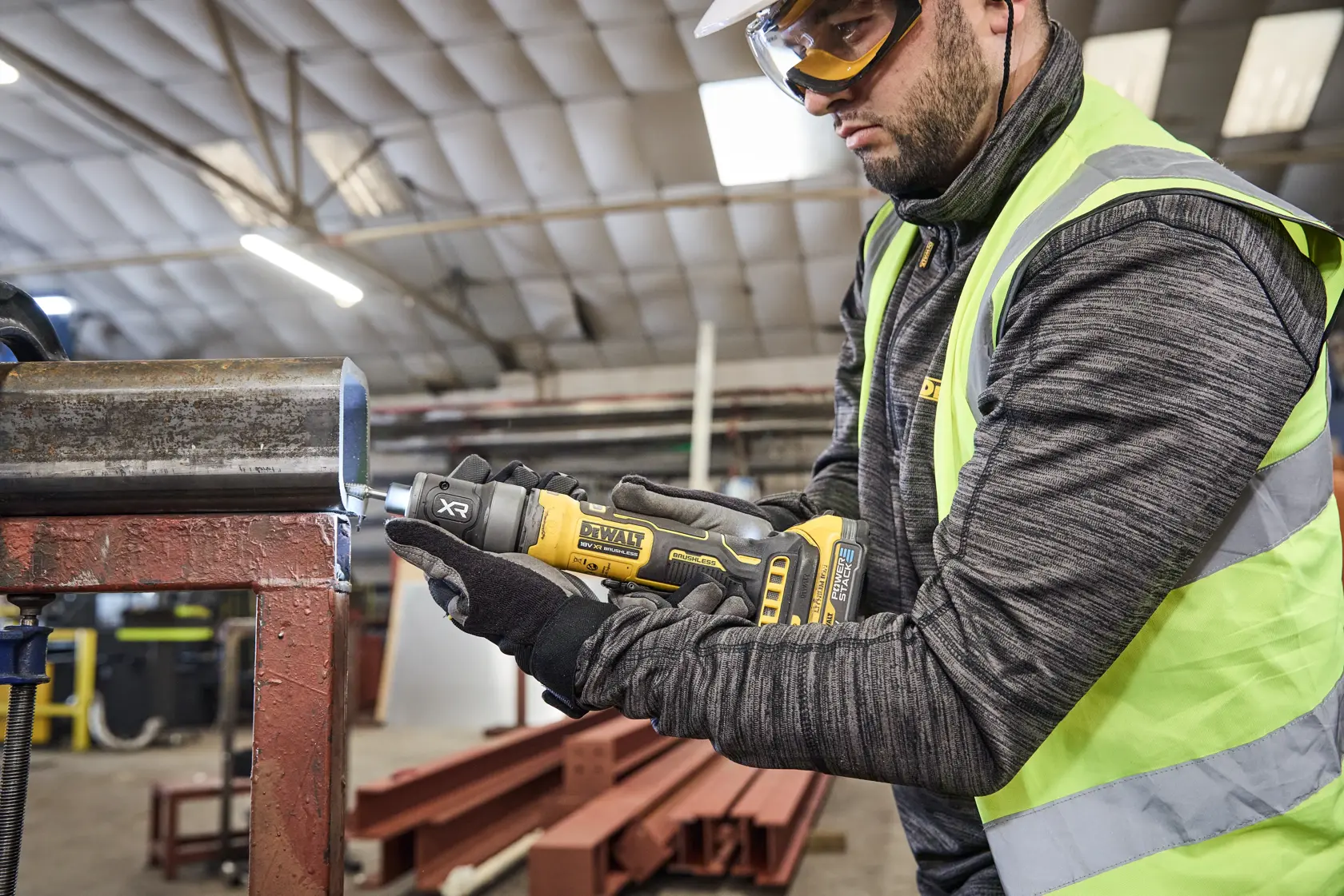 Trabajador usa DEWALT DCG420N-XJ y DCG420N en tubo metálico en entorno industrial.