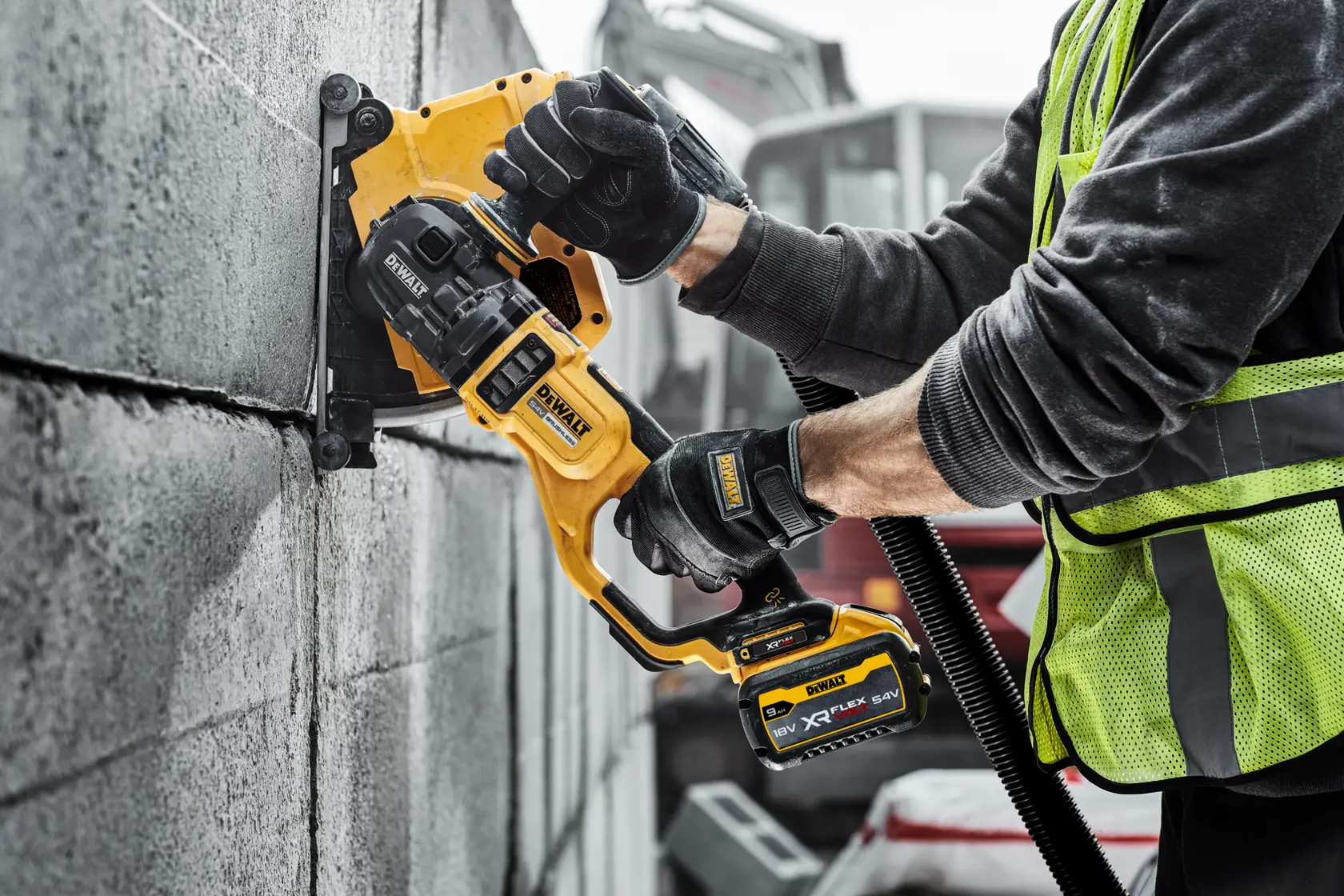 Trabajador usa una ranuradora DEWALT inalámbrica para cortar surcos en un muro de bloques de concreto.