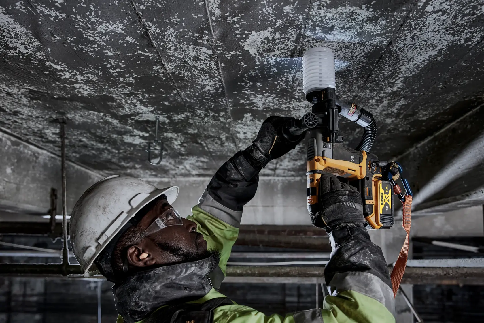 Trabajador usa DEWALT DCH172P2 en el techo, con equipo de seguridad en entorno industrial.