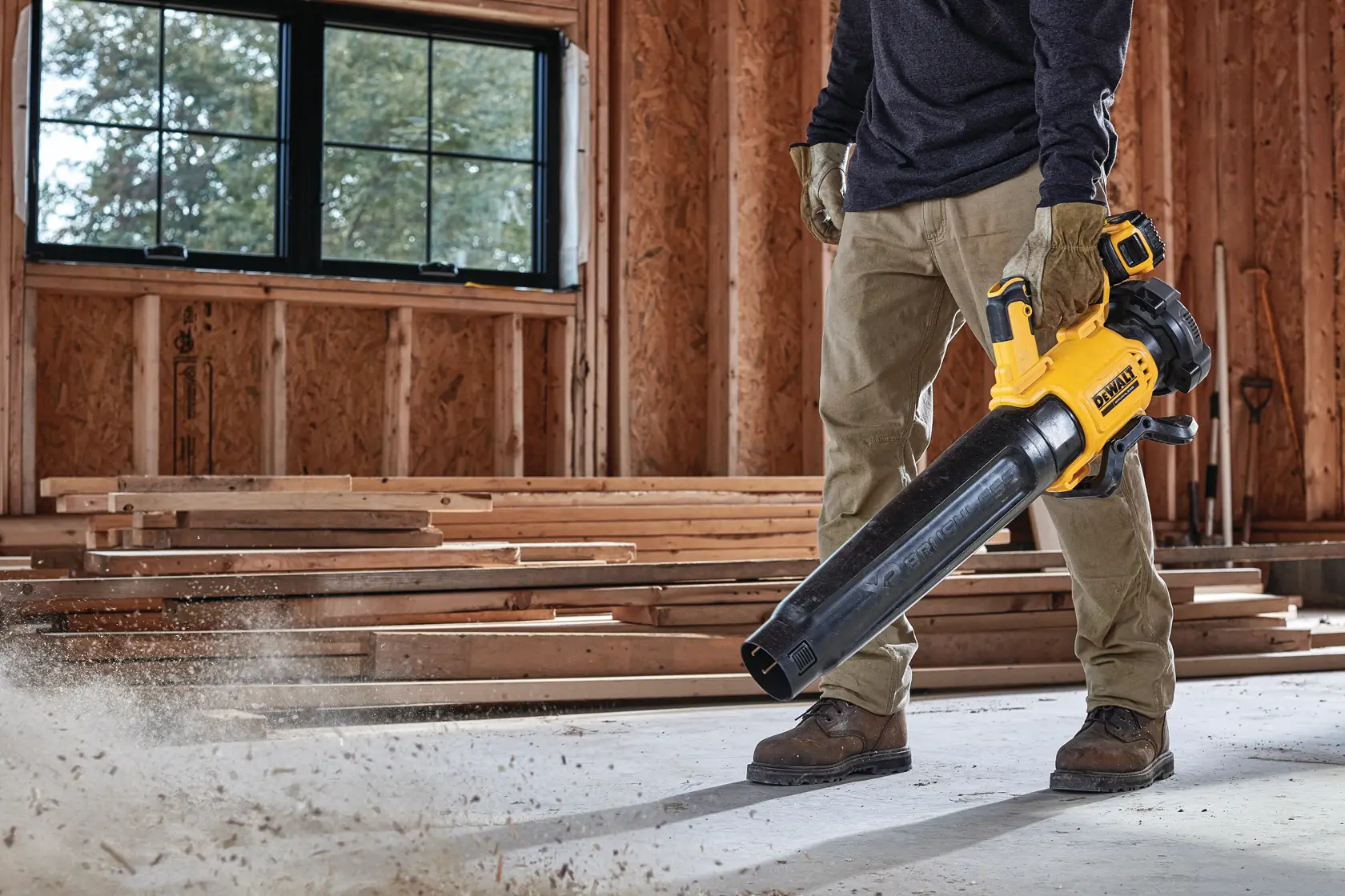 Persona limpia piso de obra con soplador amarillo DEWALT sin cable.
