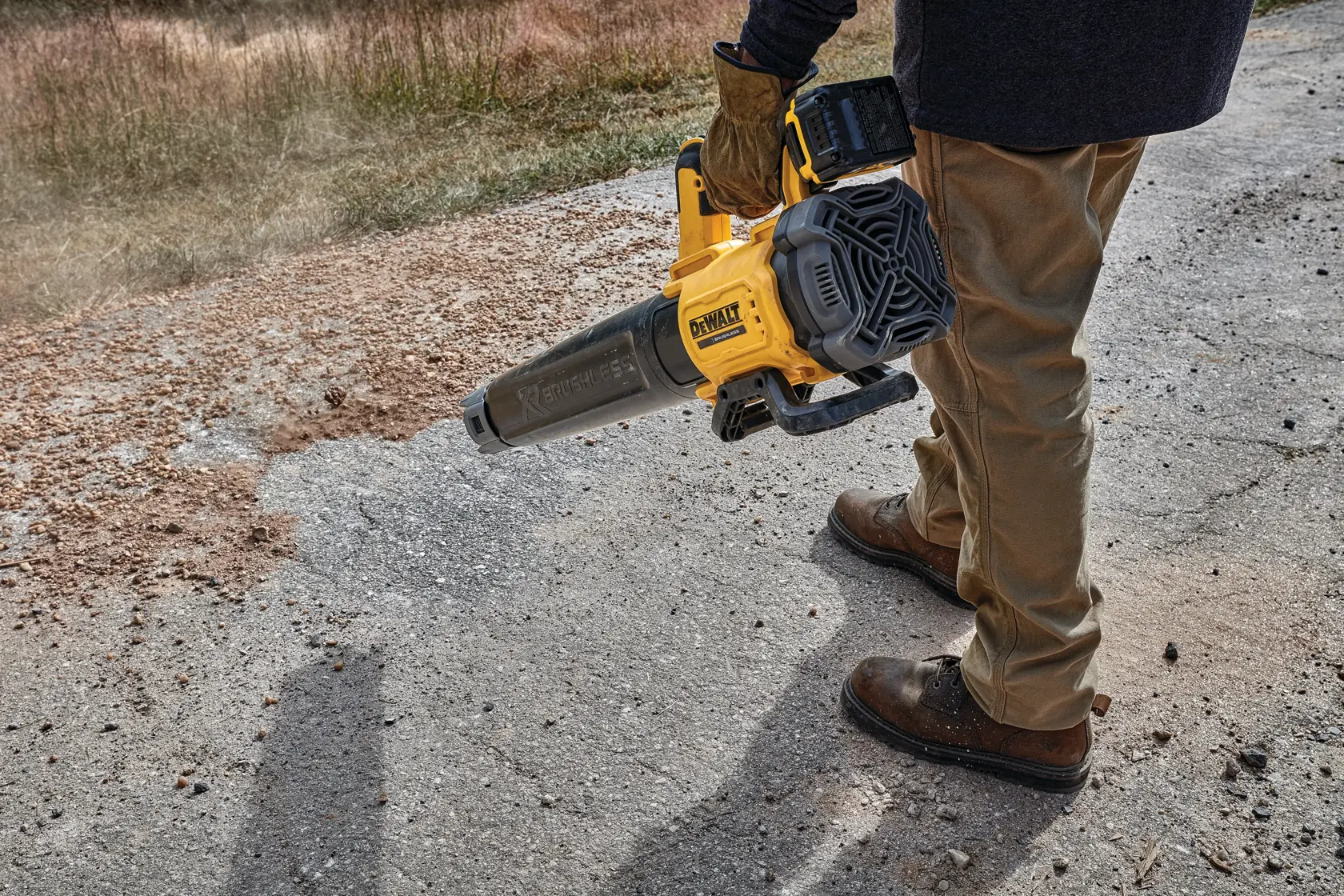 Persona usando soplador inalámbrico DEWALT para limpiar restos de una superficie exterior.