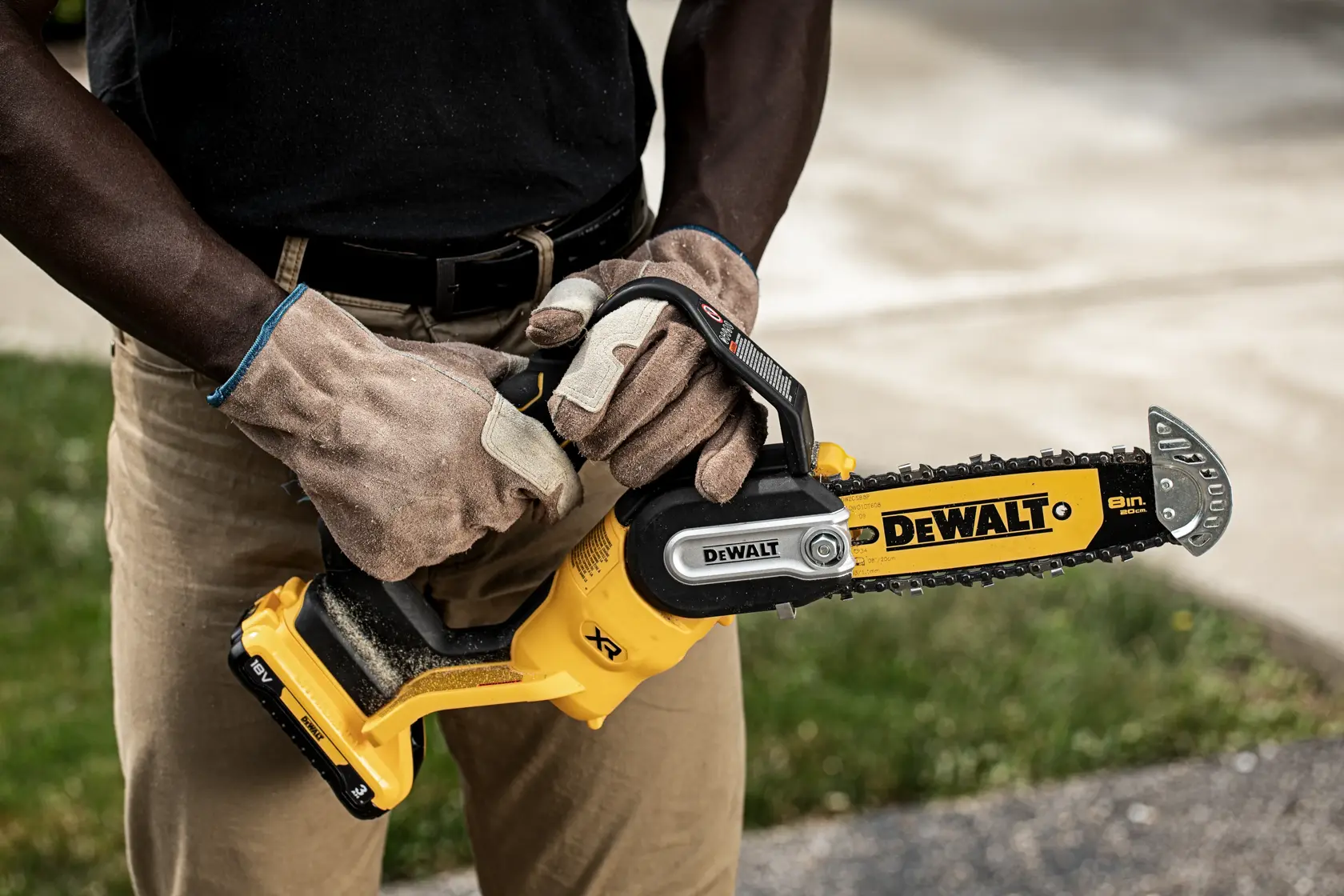 Persona con guantes sostiene una motosierra inalámbrica DEWALT DCMPS520P1 al aire libre.