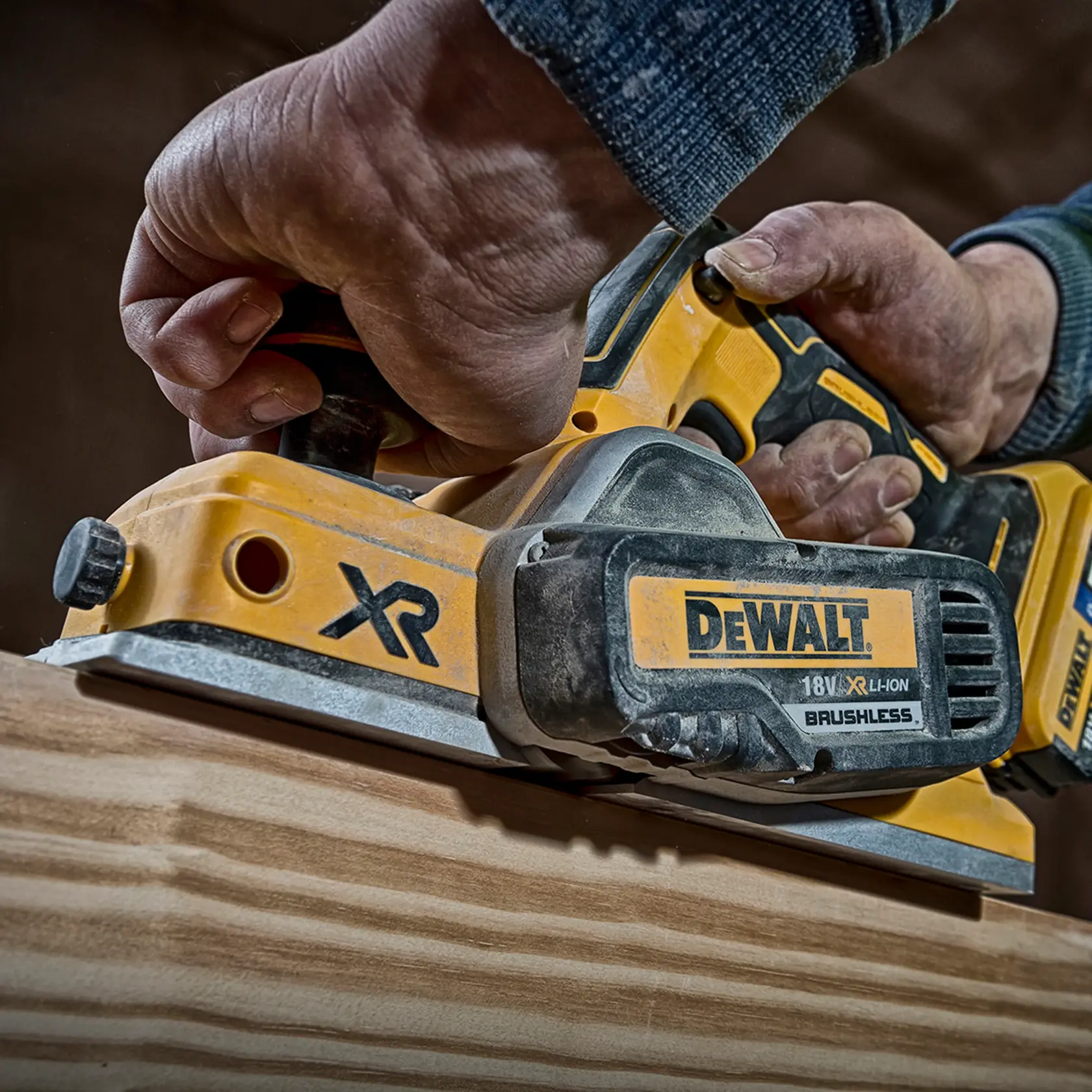 Hand uses a DEWALT DCP580P2 cordless planer to smooth wood. Close-up of tool and wood surface.