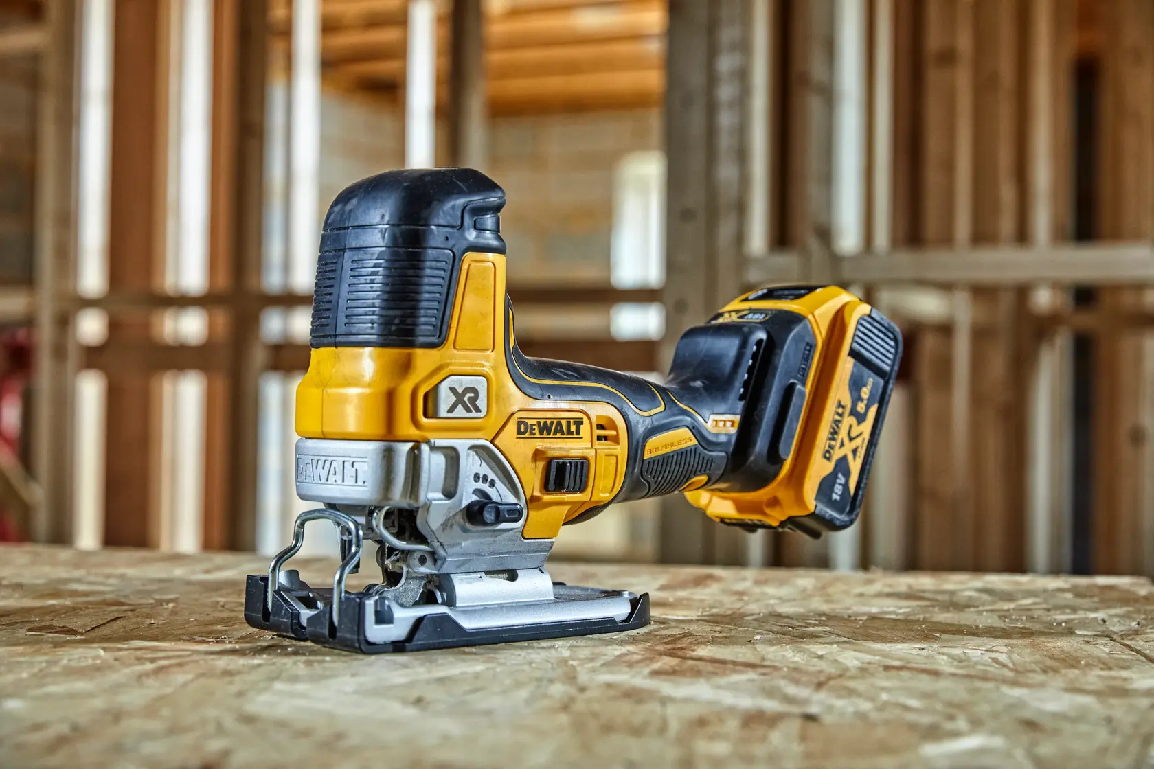 DeWalt cordless jigsaw DCS335N on a wooden surface, in a workshop with unfinished wooden walls.