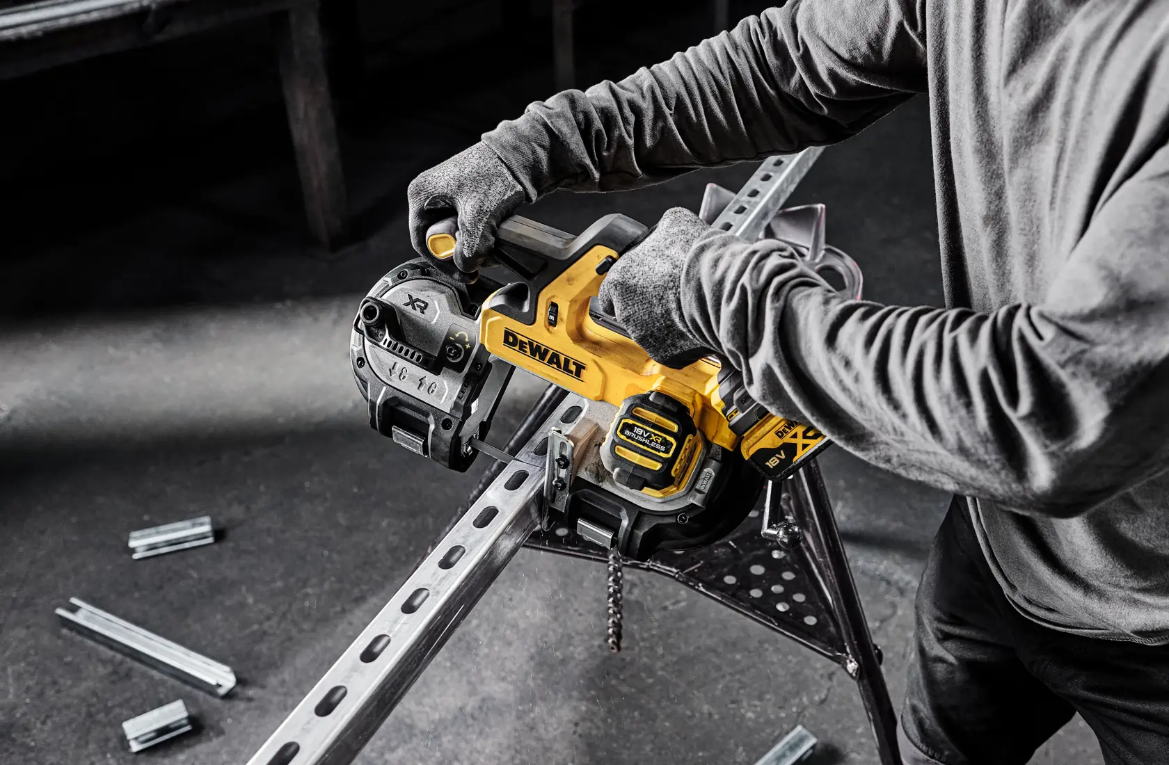Persona usa sierra de banda DEWALT sin cable para cortar viga de metal. Sierra y guantes visibles.