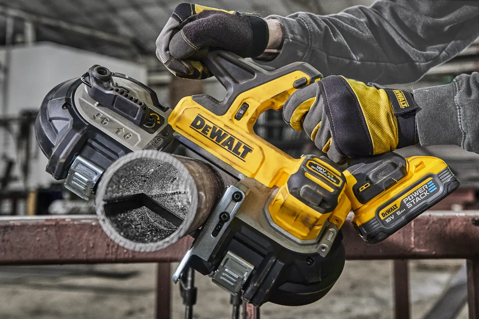 Sierra de banda inalámbrica DEWALT cortando tubo metálico, sostenida por manos con guantes en taller.