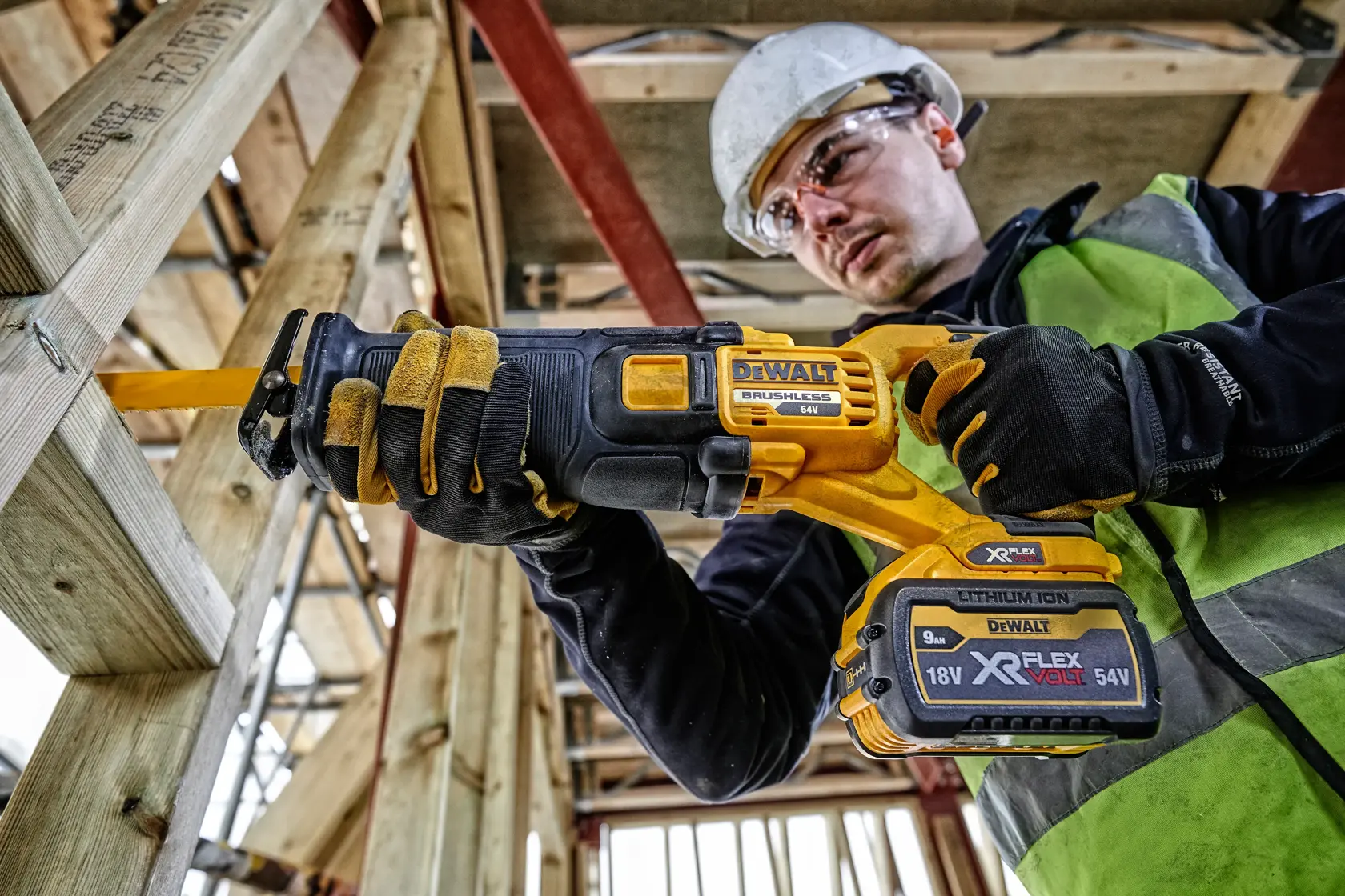 Trabajador usa sierra DEWALT DCS389NT para cortar madera en obra, con guantes y equipo de seguridad.