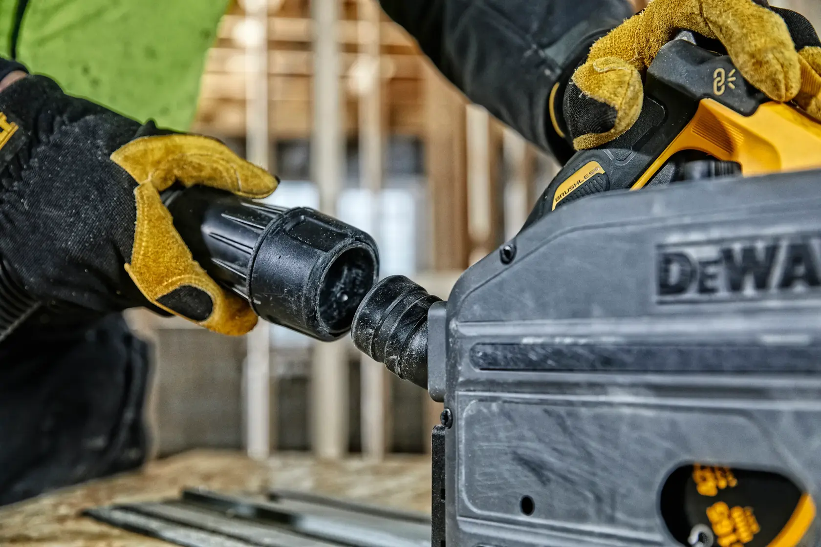 Behandschuhte Hände verbinden einen Schlauch mit einem DEWALT Werkzeug auf einer Baustelle.