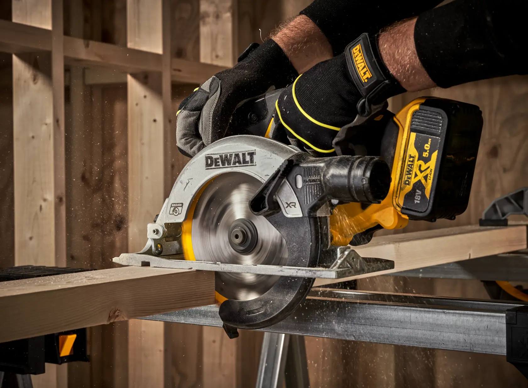 DEWALT DCS565N cordless circular saw cutting wood, operated by gloved hands in a workshop.