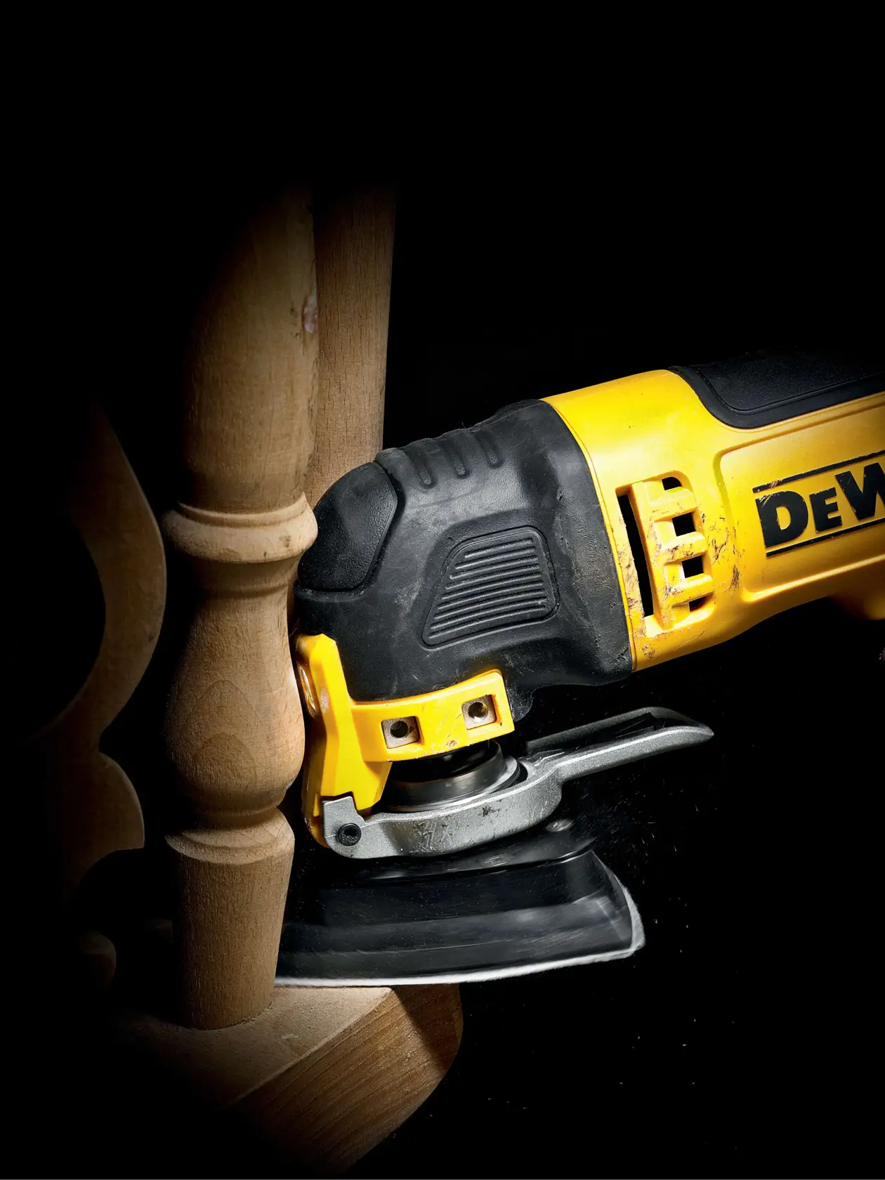 DEWALT Multitool schleift Holzmöbel im Nahbereich, Präzisionsarbeit sichtbar.