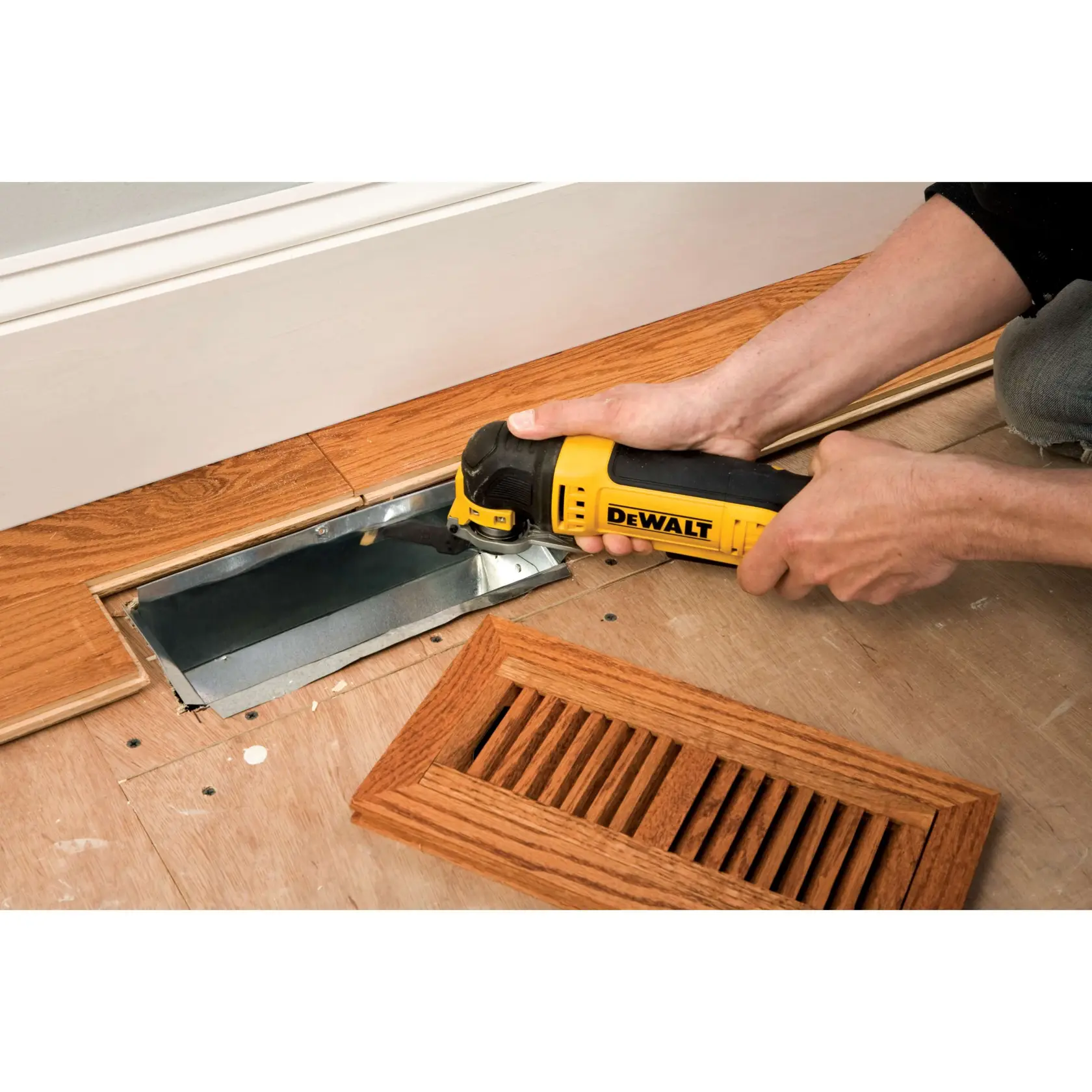 DEWALT DT20702 Werkzeug schneidet Holzboden am Lüftungsschacht, Holzabdeckung liegt daneben.
