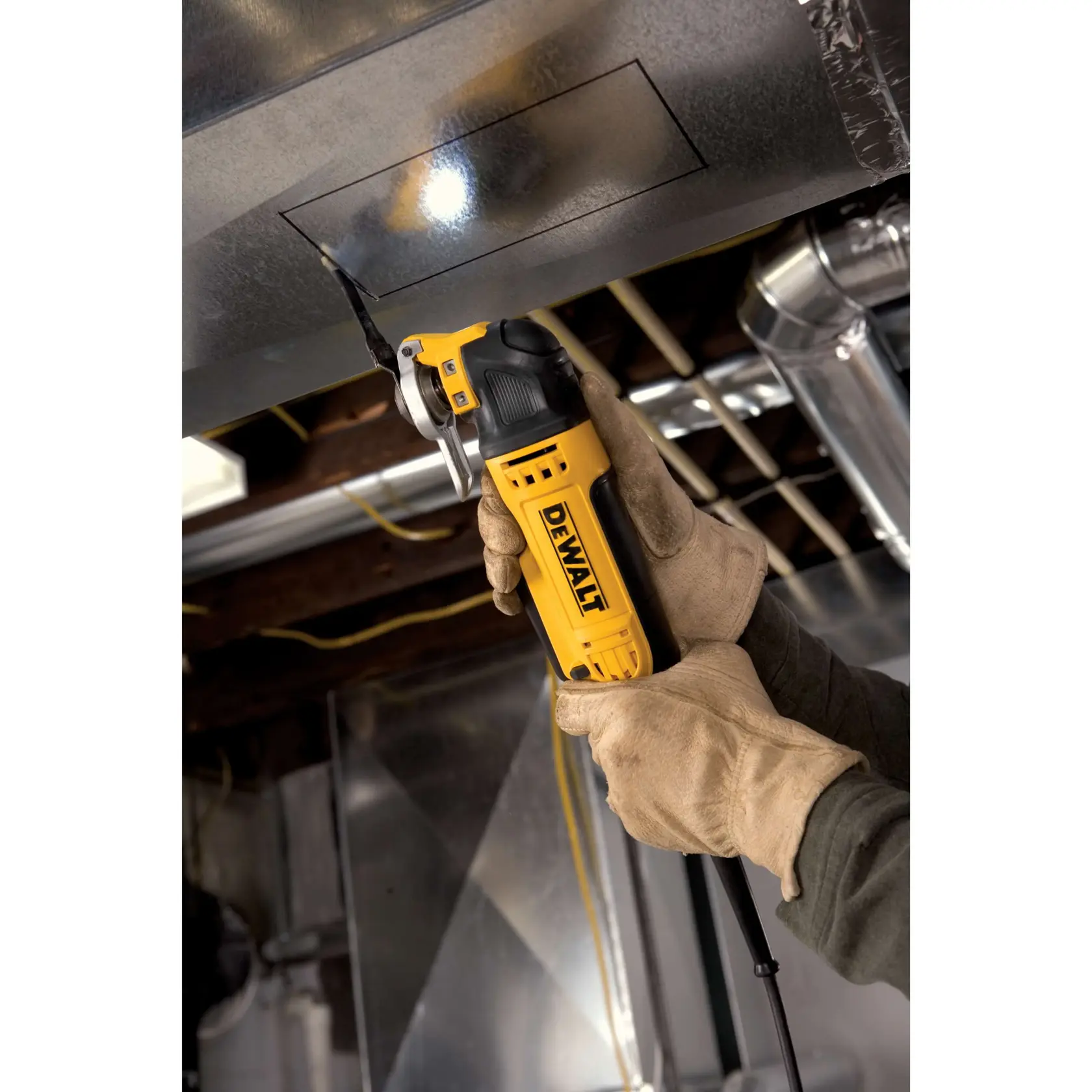 Behandschuhte Hände schneiden mit einem DEWALT Oszillationswerkzeug einen rechteckigen Ausschnitt in ein Metallrohr.