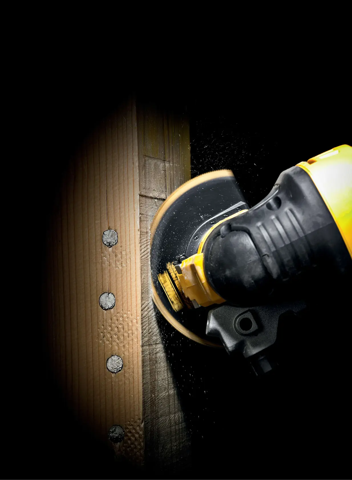 DEWALT power tool cutting through a wooden plank with visible screws, shown close-up in action.