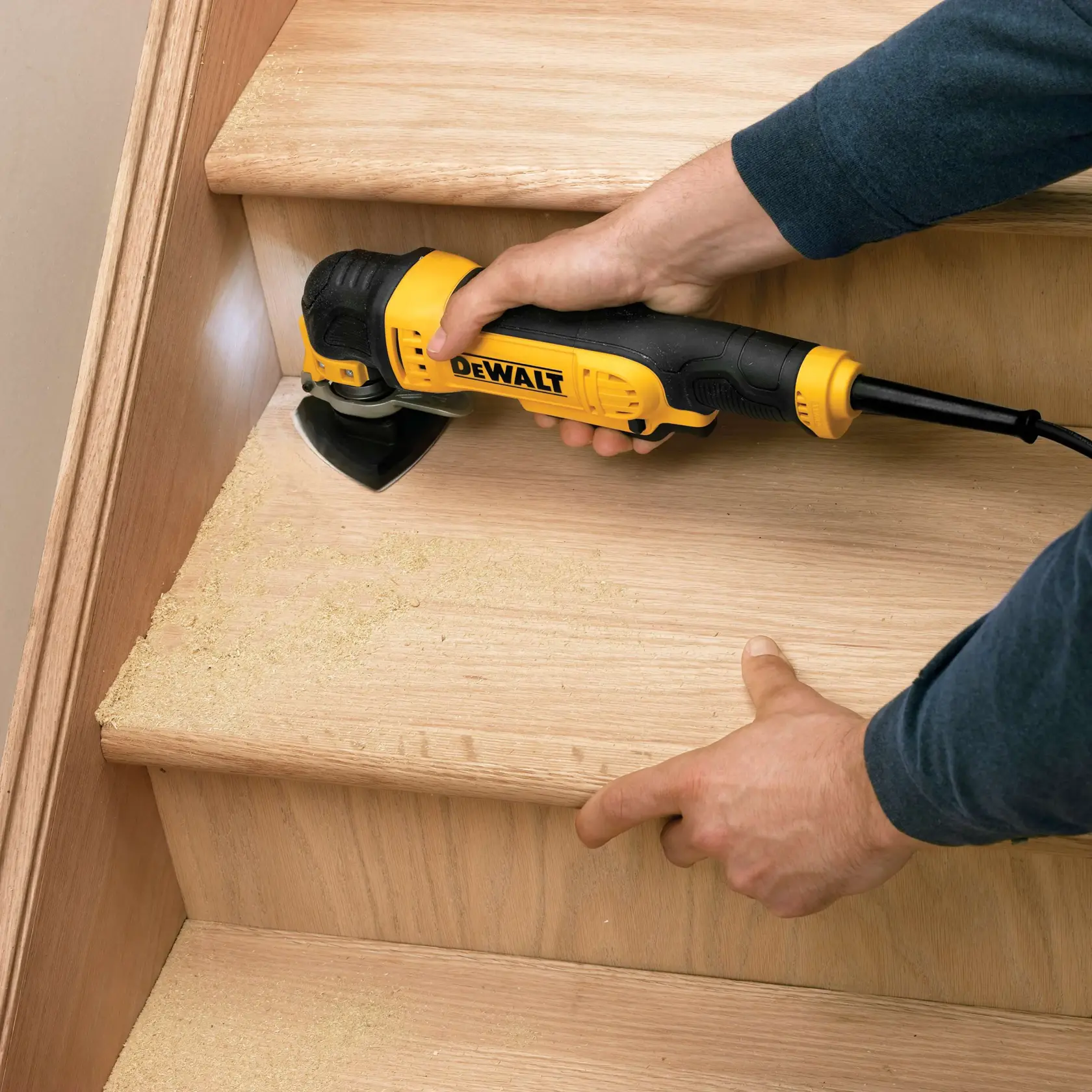 Persona lija escalera de madera con herramienta DEWALT, generando polvo de madera al lijar.