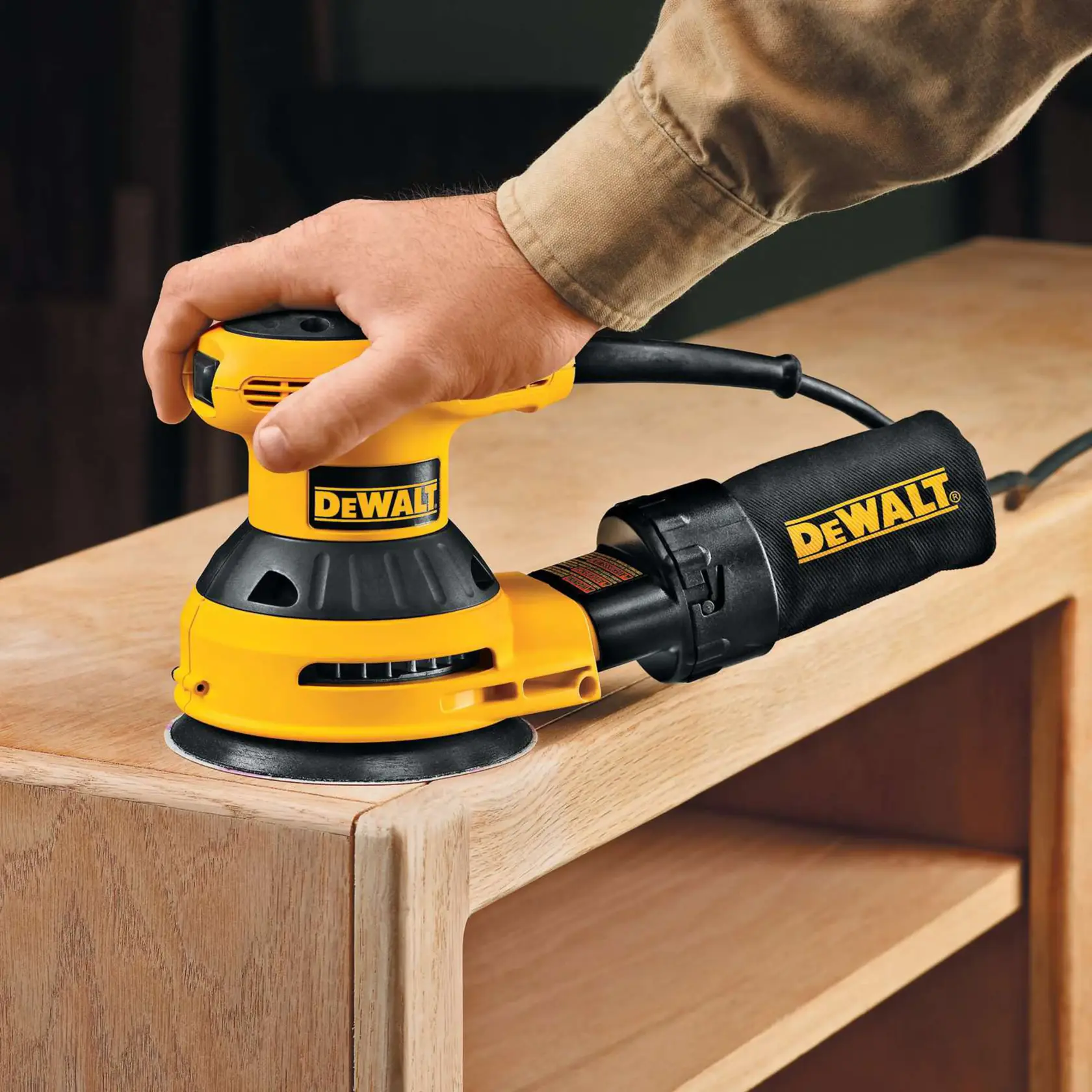 A DEWALT sander is used to smooth a wooden cabinet surface.