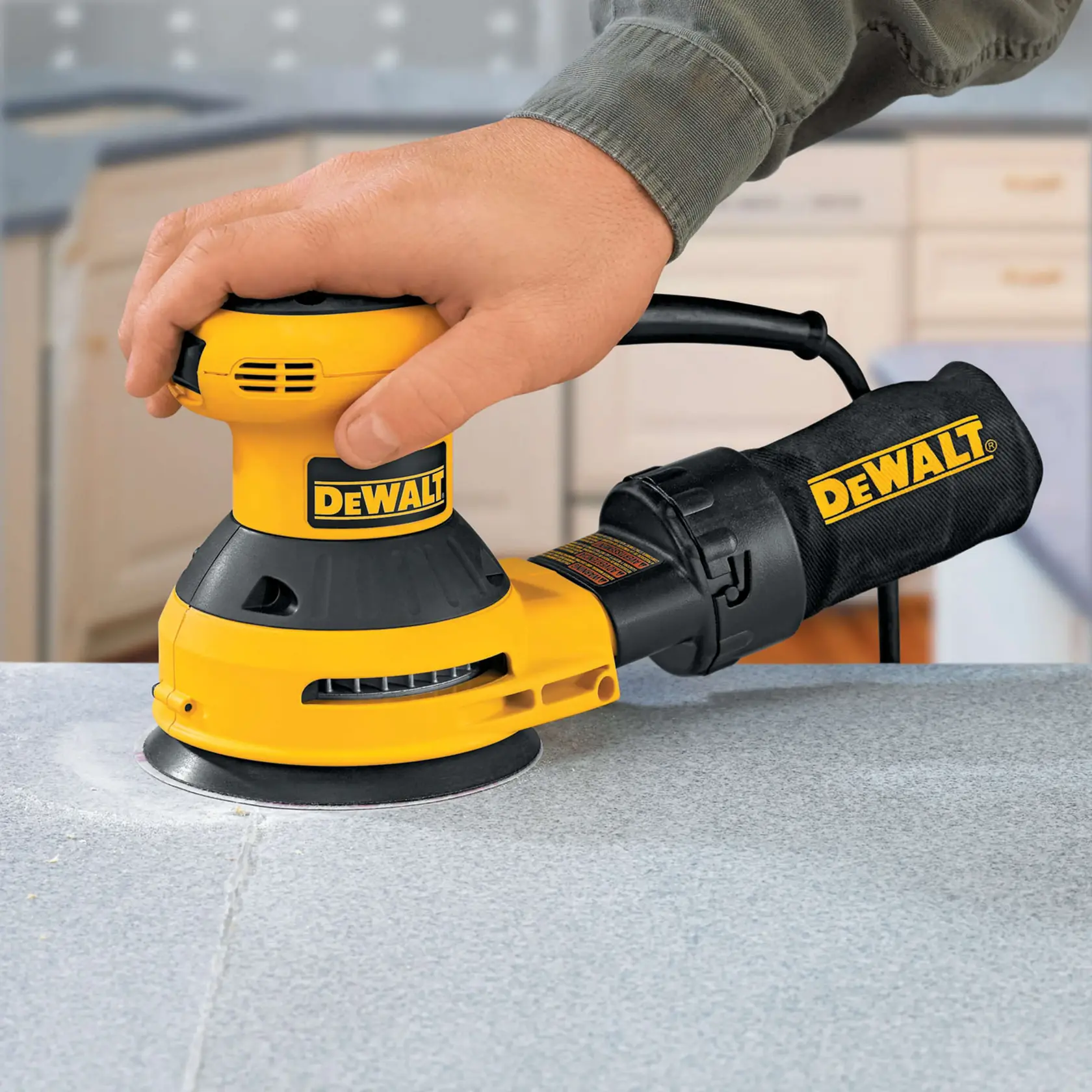 DEWALT handheld sander is being used to smooth a countertop surface in a home setting.