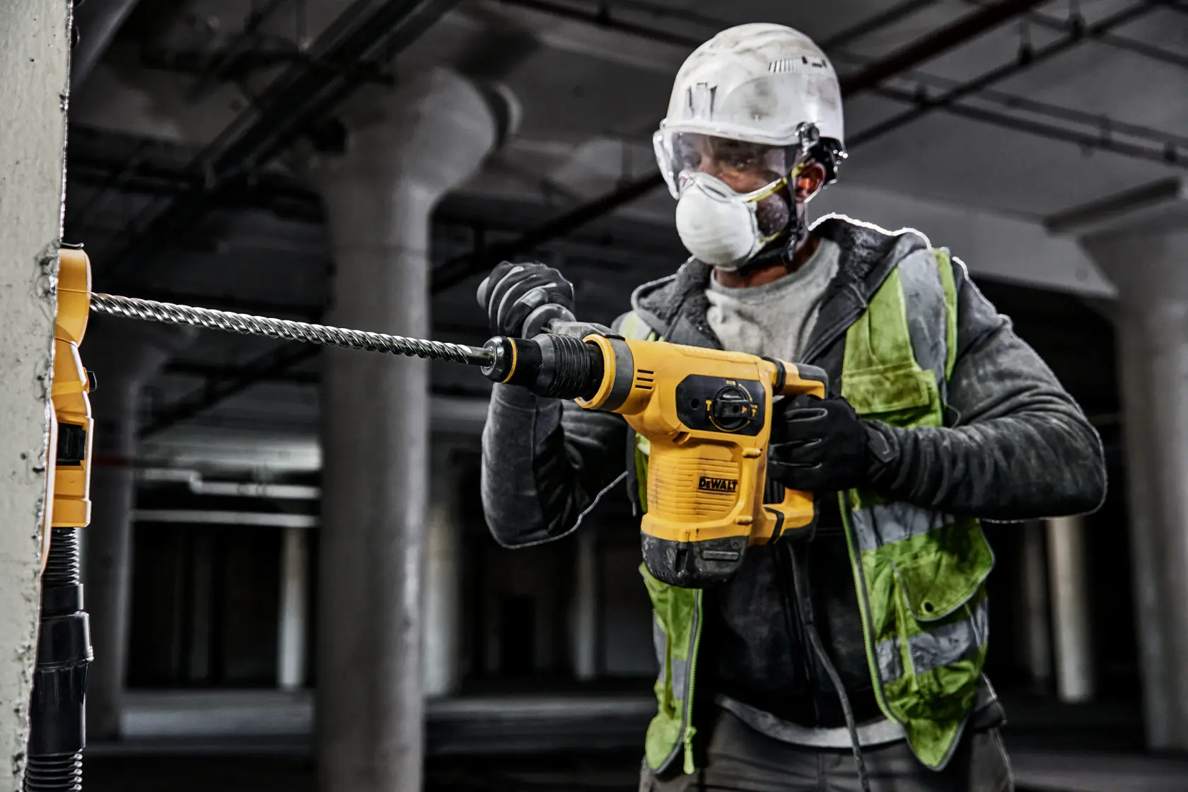 Trabajador usa taladro DEWALT DT60820, DT60820-QZ en concreto; obra interior, lleva protección.