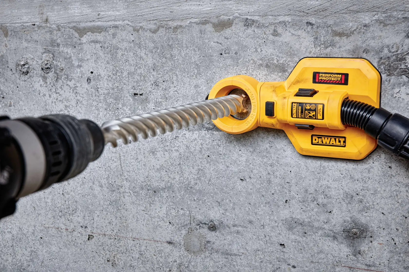 DEWALT DT60830 Staubabsauger an einem Bohrer, verwendet an einer Betonwand.