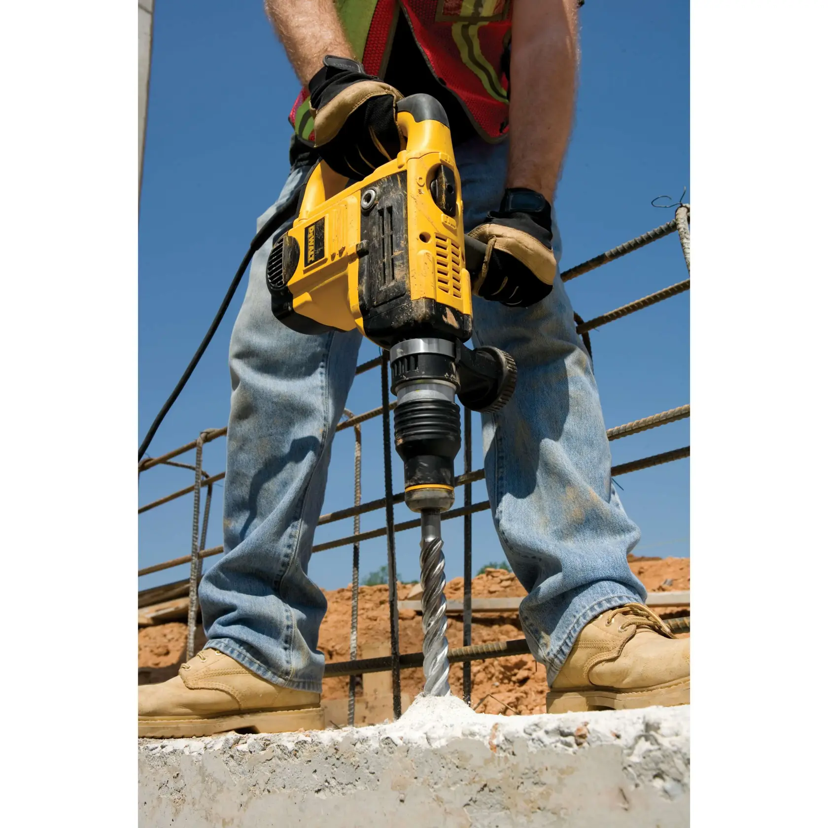 Persona usando taladro rotativo DEWALT para perforar concreto en un sitio de construcción.