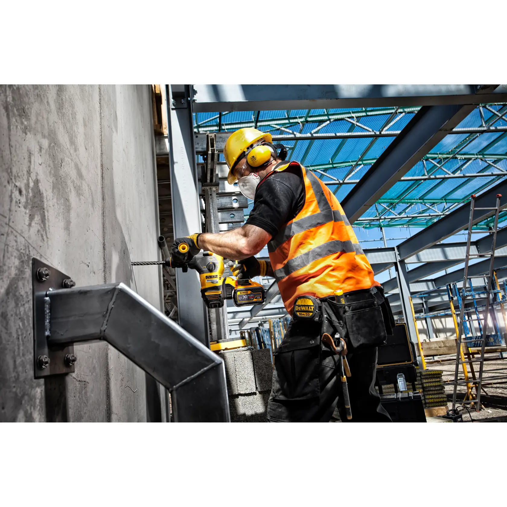 Trabajador perfora pared de concreto con herramienta DEWALT, lleva chaleco naranja y equipo de seguridad.