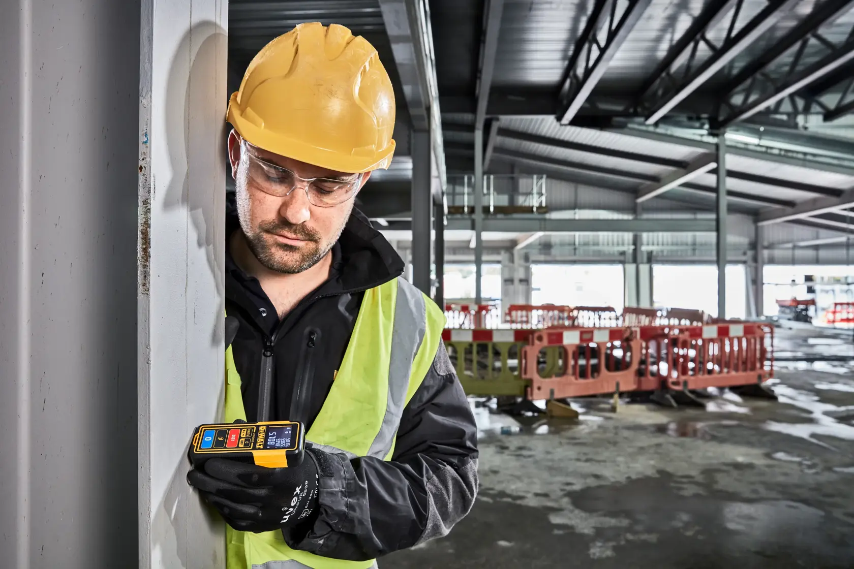 Télémètre laser DEWALT DW099S avec un écran numérique lumineux affichant plusieurs lectures de mesure. L'appareil a un corps jaune et noir, avec des boutons étiquetés pour des fonctions telles que unités, distance et Bluetooth.