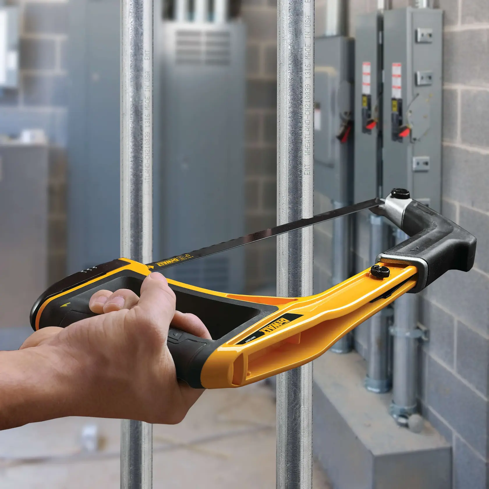 Mano usando sierra DEWALT para cortar tubo metálico en entorno industrial junto a paneles eléctricos.