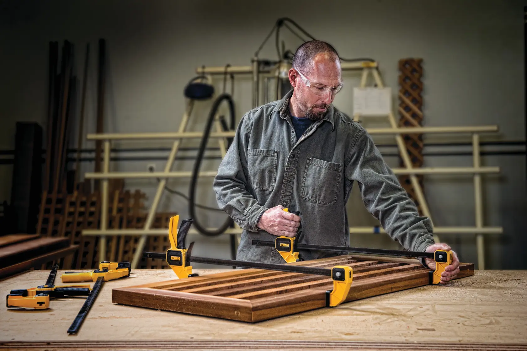 Persona usa abrazaderas DEWALT para sujetar tablas de madera en un banco de trabajo en taller.