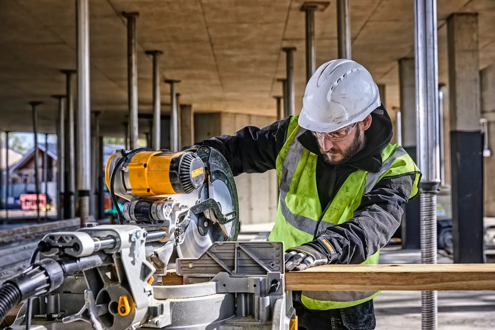 DEWALT DWS780, DWS780KIT saw in use at a construction site. Worker wears safety gear. Photography product category.