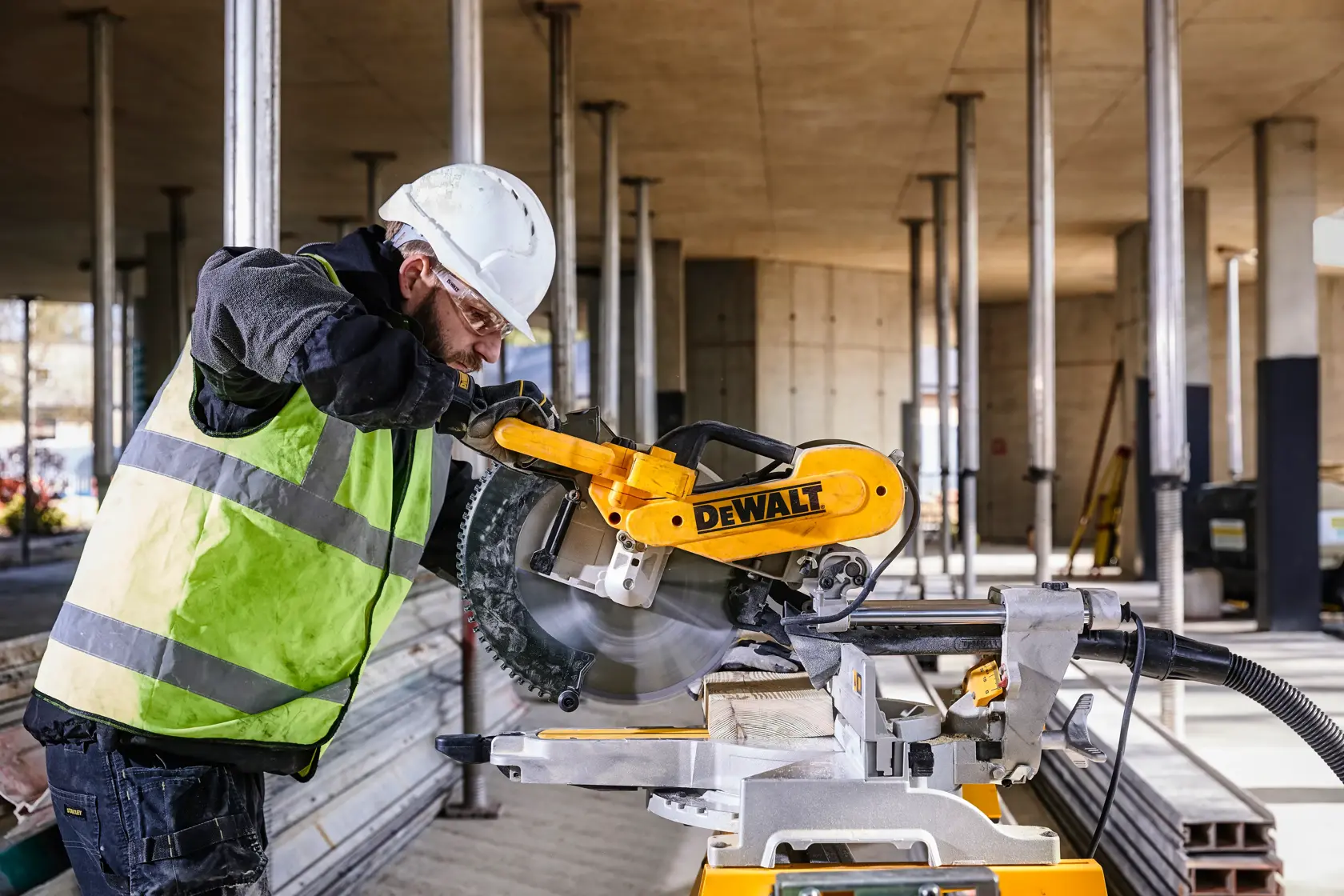 DEWALT DWS780, DWS780KIT miter saw in use at a building site. Worker cuts wood. Photography product category.