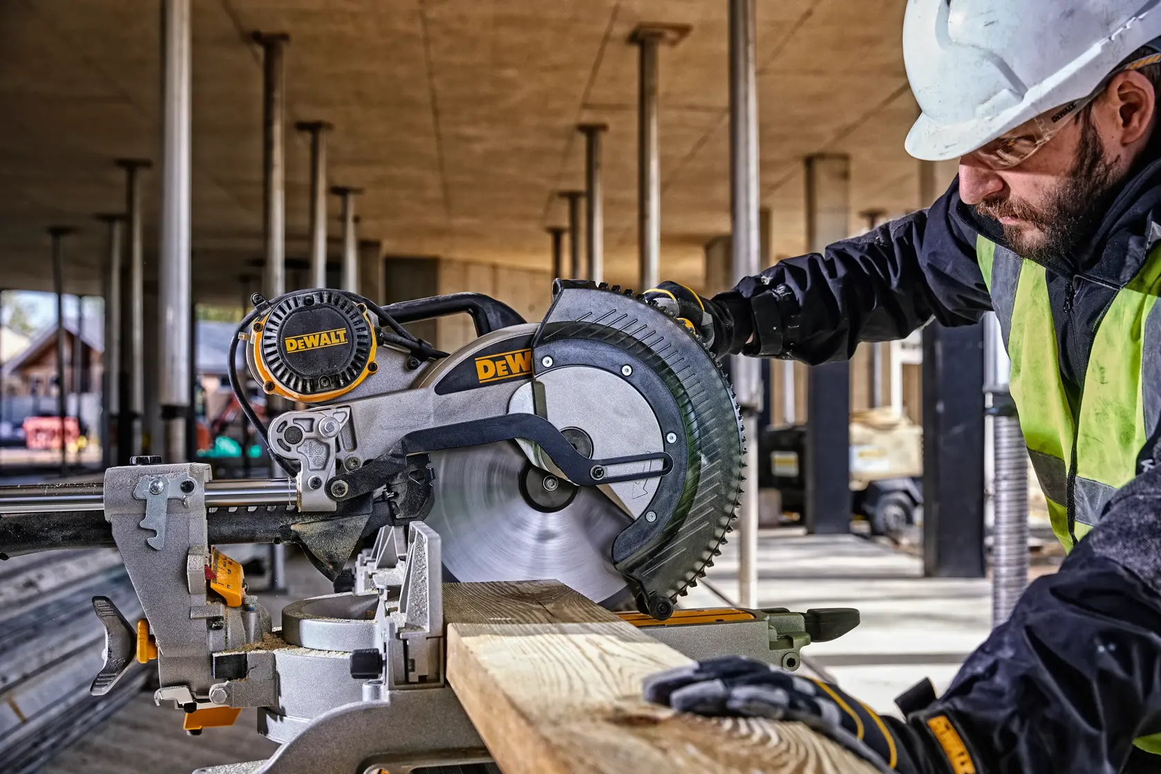 DEWALT DWS780, DWS780KIT saw in use at construction site, worker with helmet and vest. Photography category.