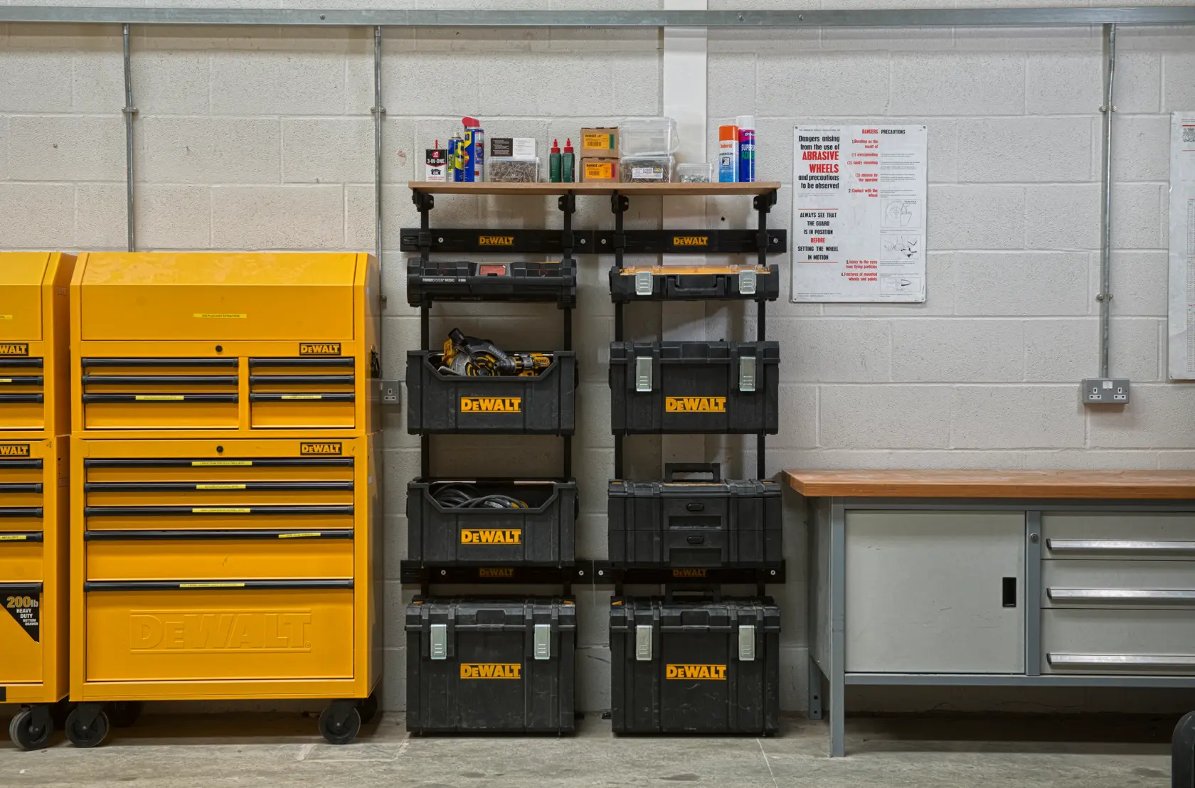 Cajas DEWALT y estantes organizados junto a banco de trabajo y armarios amarillos en taller.