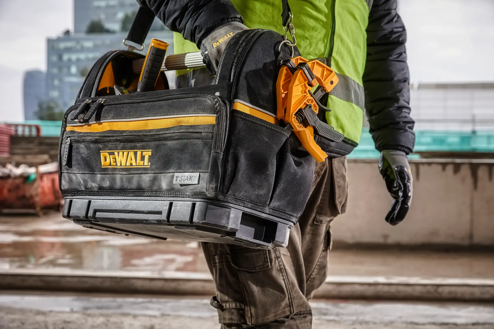 Bolsa de herramientas DEWALT con herramientas, llevada por un trabajador en obra exterior.