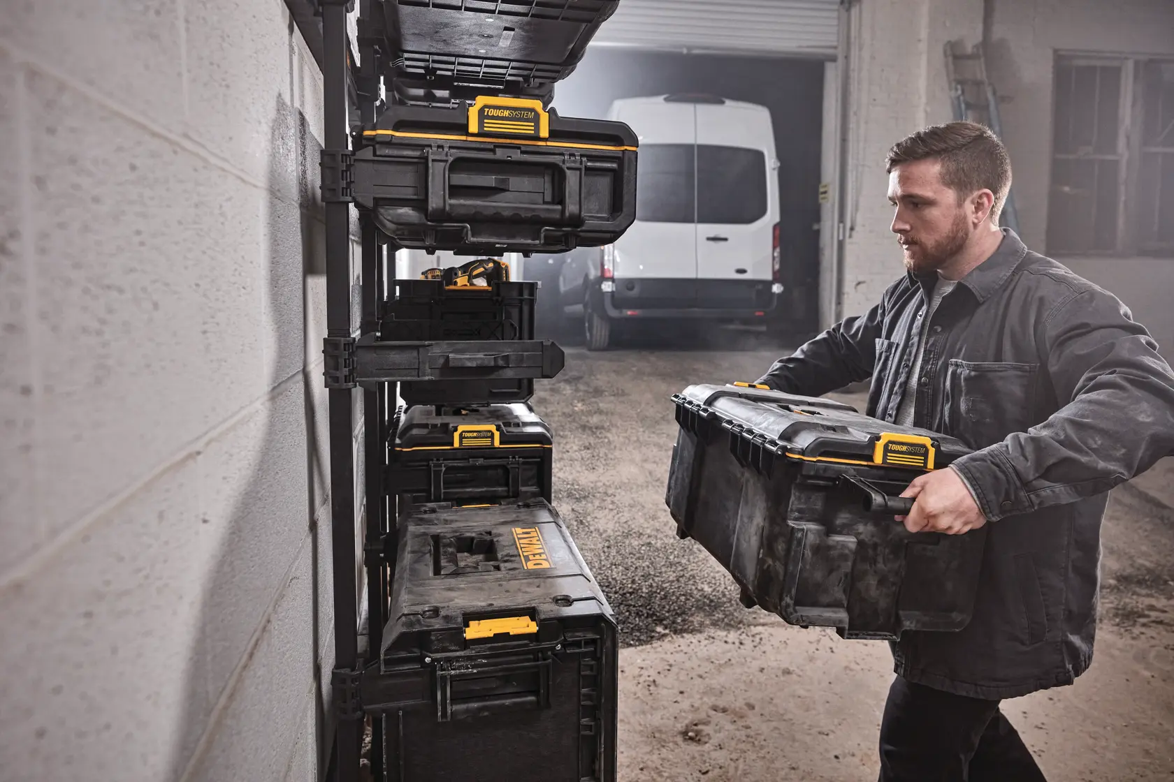 Person stellt einen DEWALT Werkzeugkasten auf ein Wandregal in einer Garage mit gestapelten Boxen.