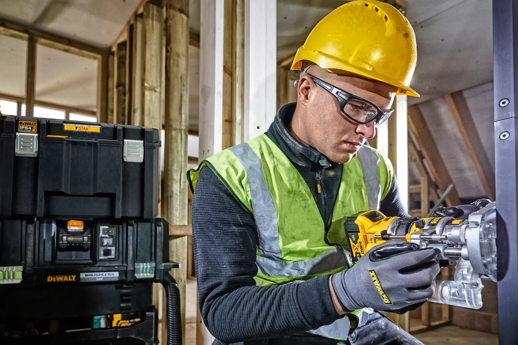 Trabajador con casco usa herramienta DEWALT, caja DEWALT al fondo en el sitio de construcción.