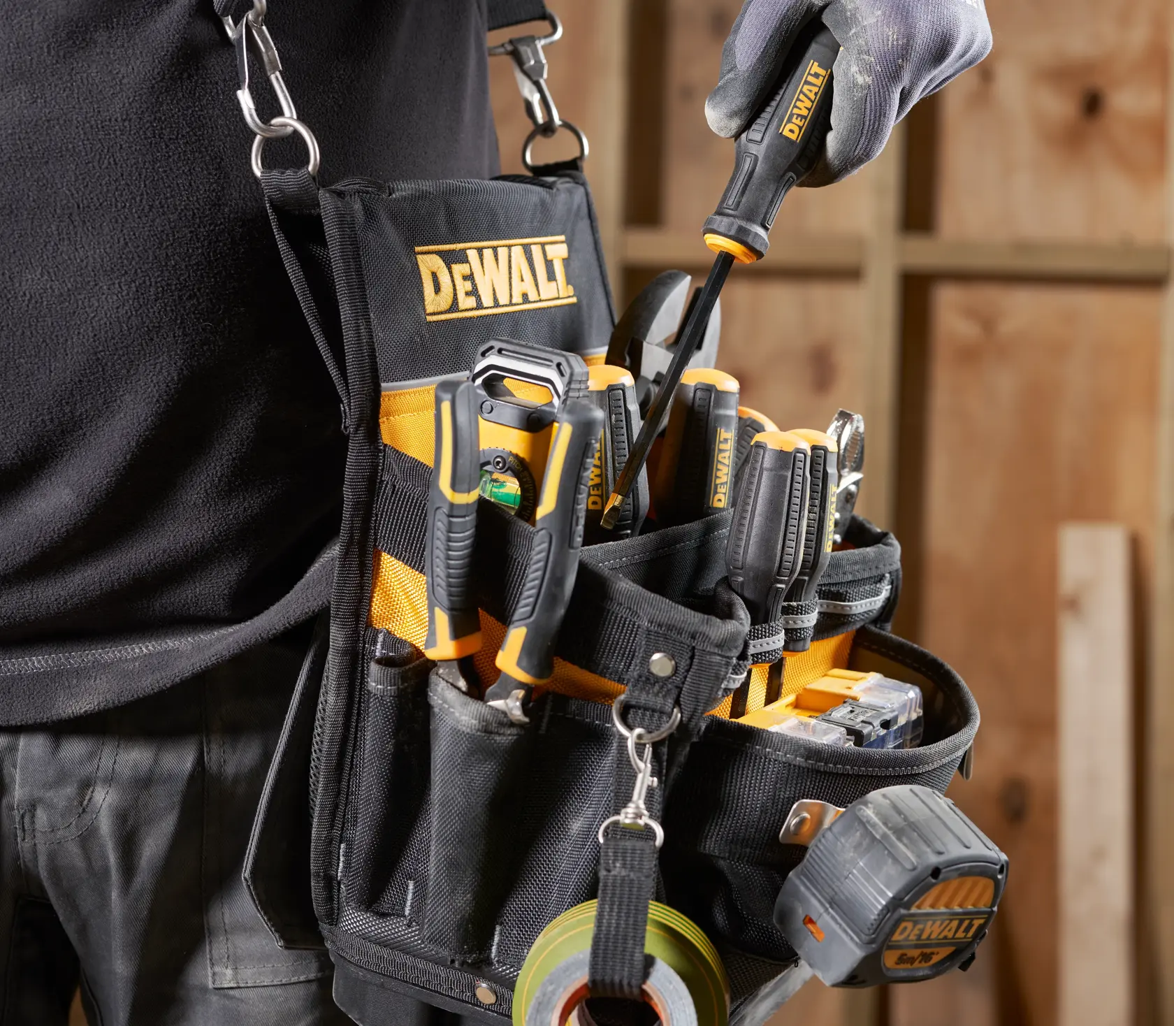 DEWALT Werkzeuggürtel mit verschiedenen Werkzeugen und Maßband in einer Werkstatt.